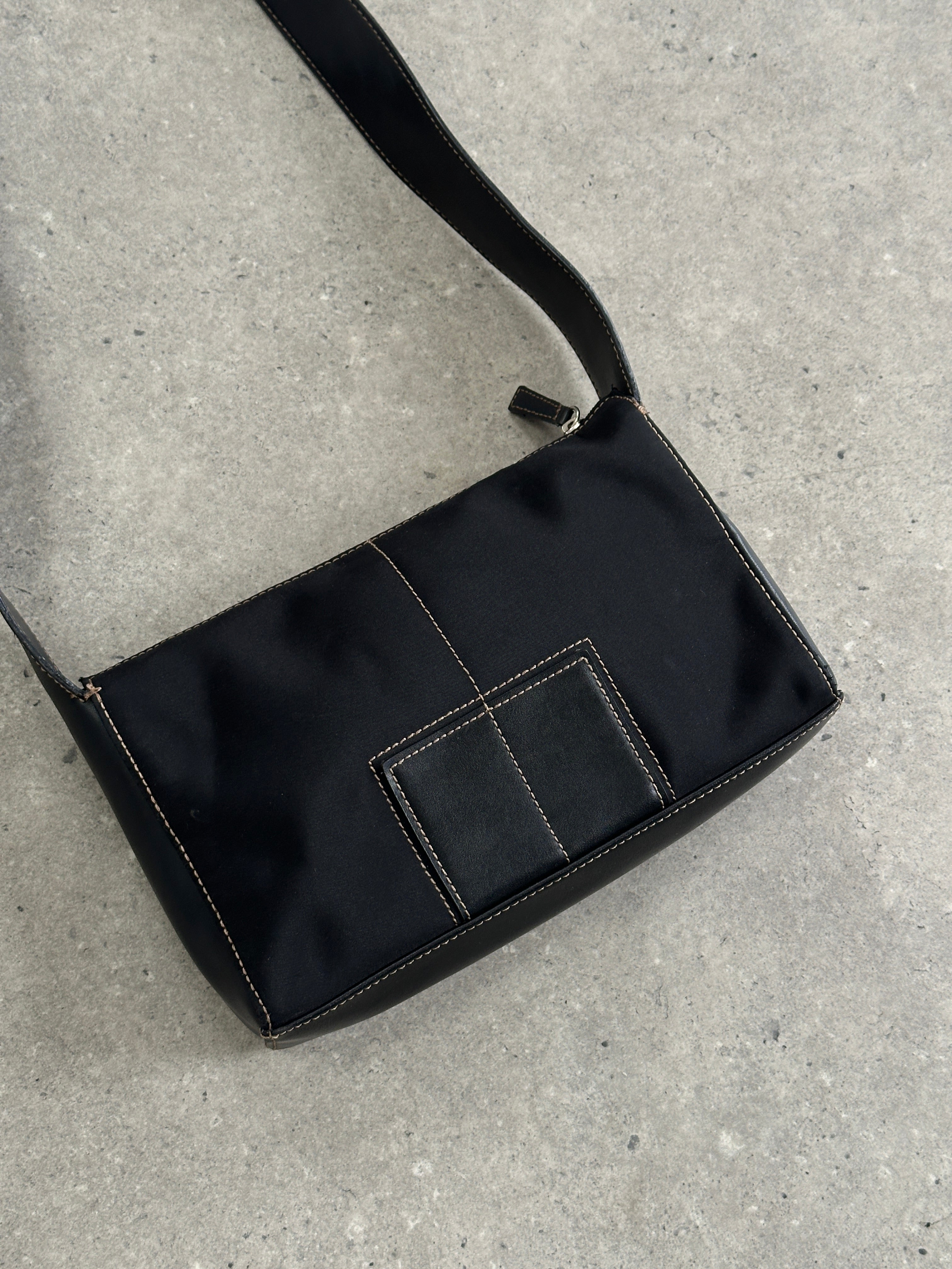 DKNY contrast stitch crossbody bag with adjustable strap and sleek design, showcasing modern style and practical storage.