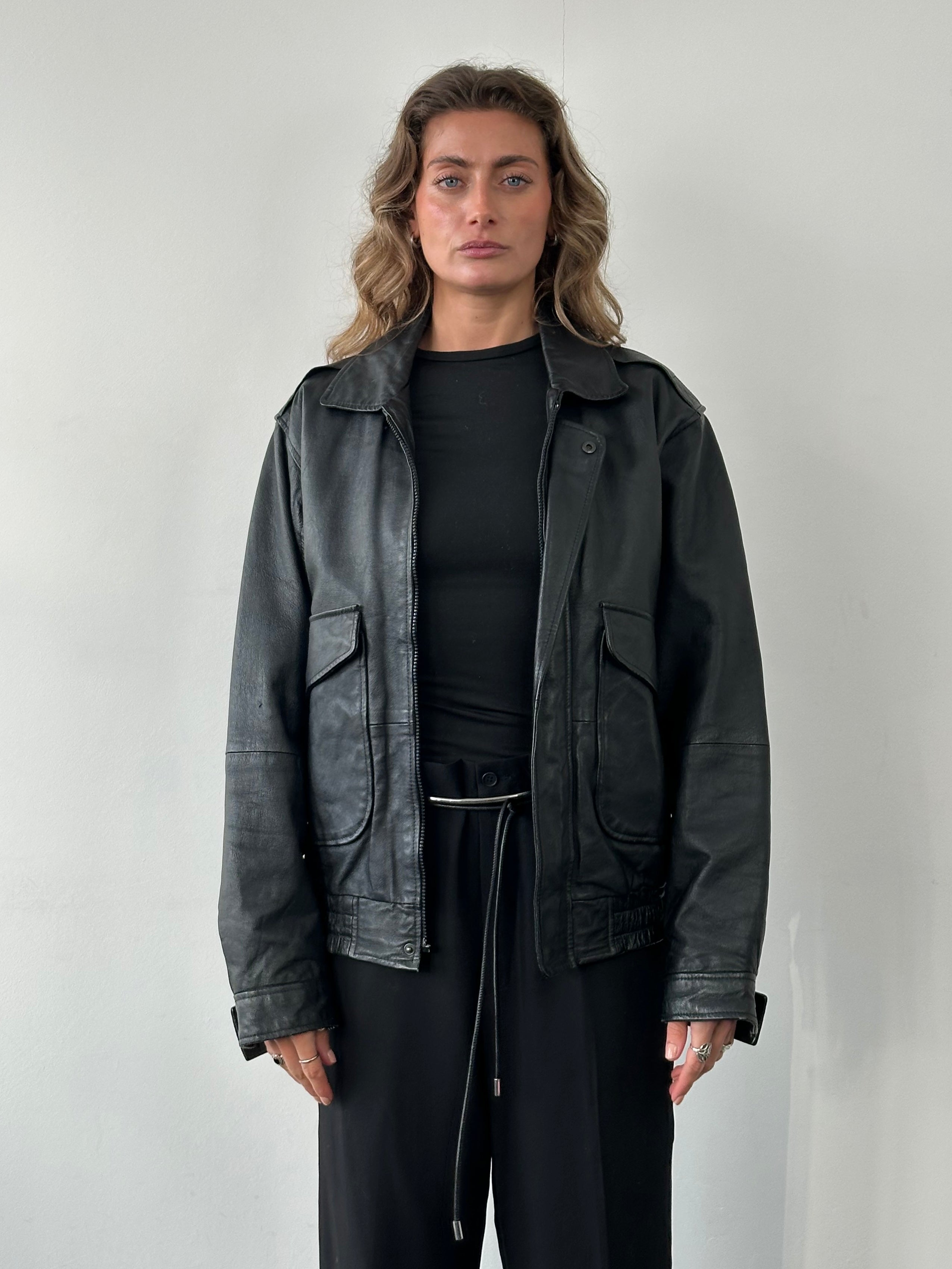 Vintage leather bomber jacket in size M/L, featuring classic design, ribbed cuffs, and front zipper details.