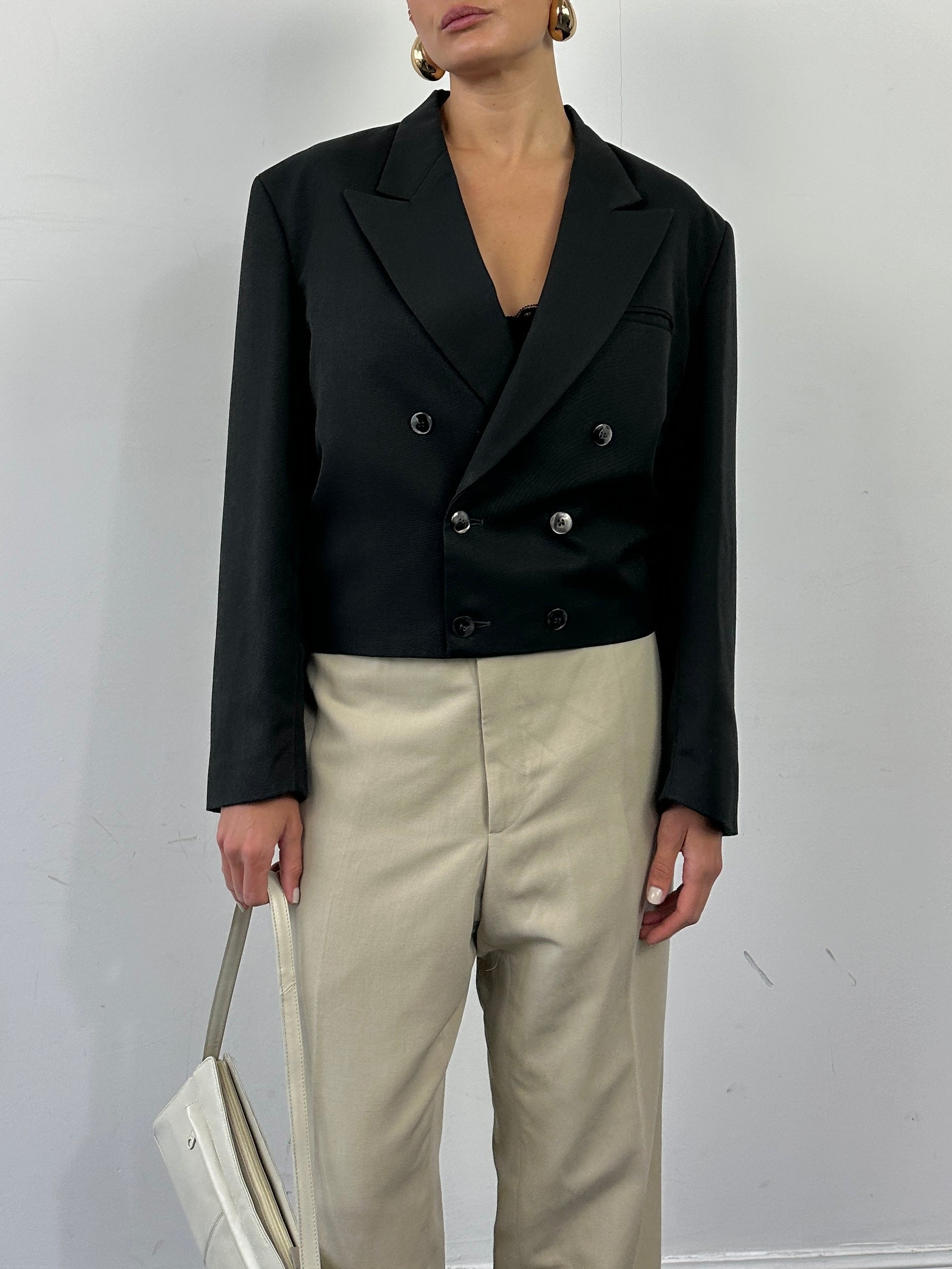 Vintage 1980s cropped double-breasted blazer in classic style, displayed on a hanger showcasing its tailored fit and vintage fabric.