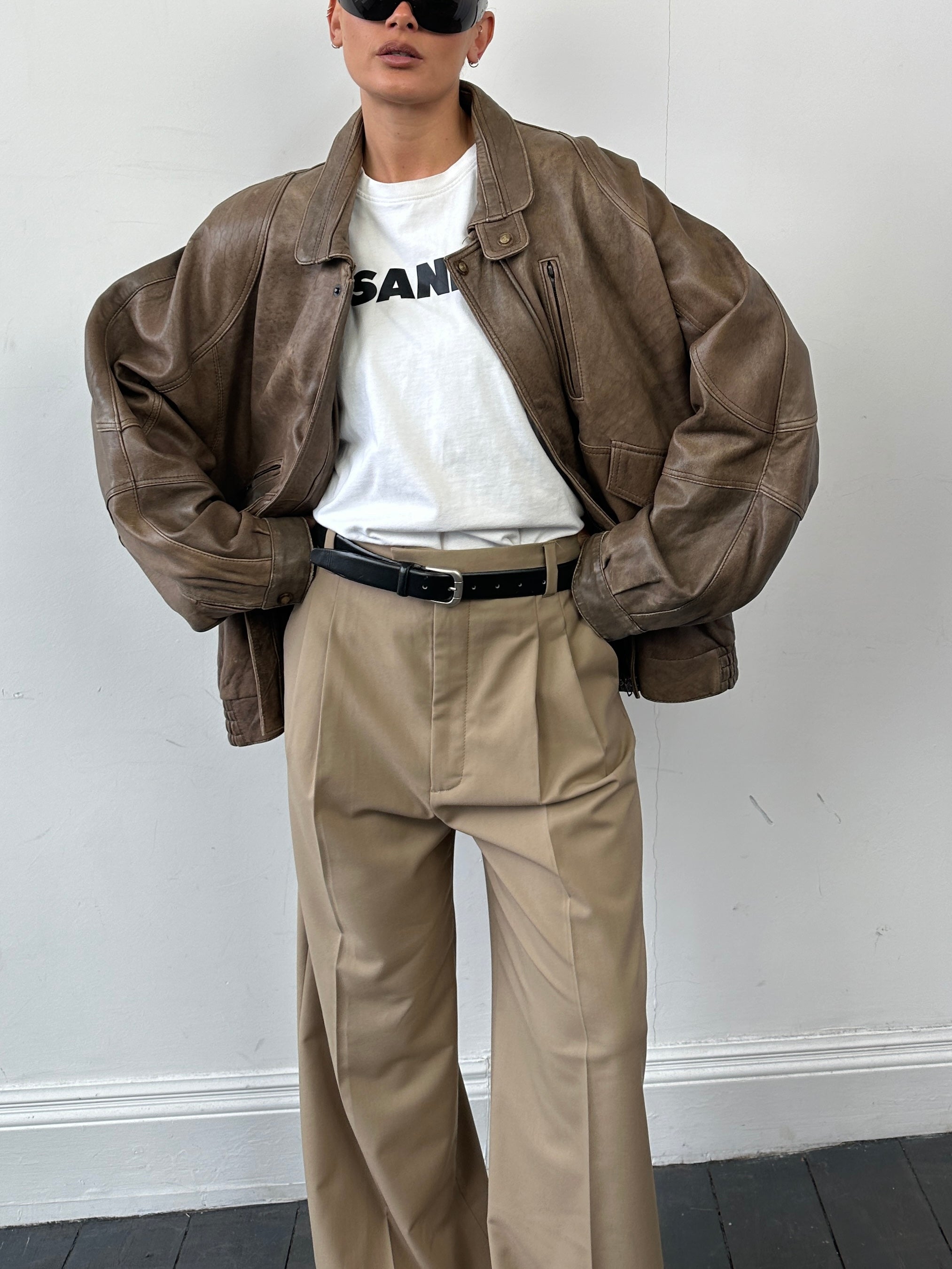 Vintage leather bomber jacket in XL/XXL size, featuring classic design, brown leather, and ribbed cuffs on a hanger.