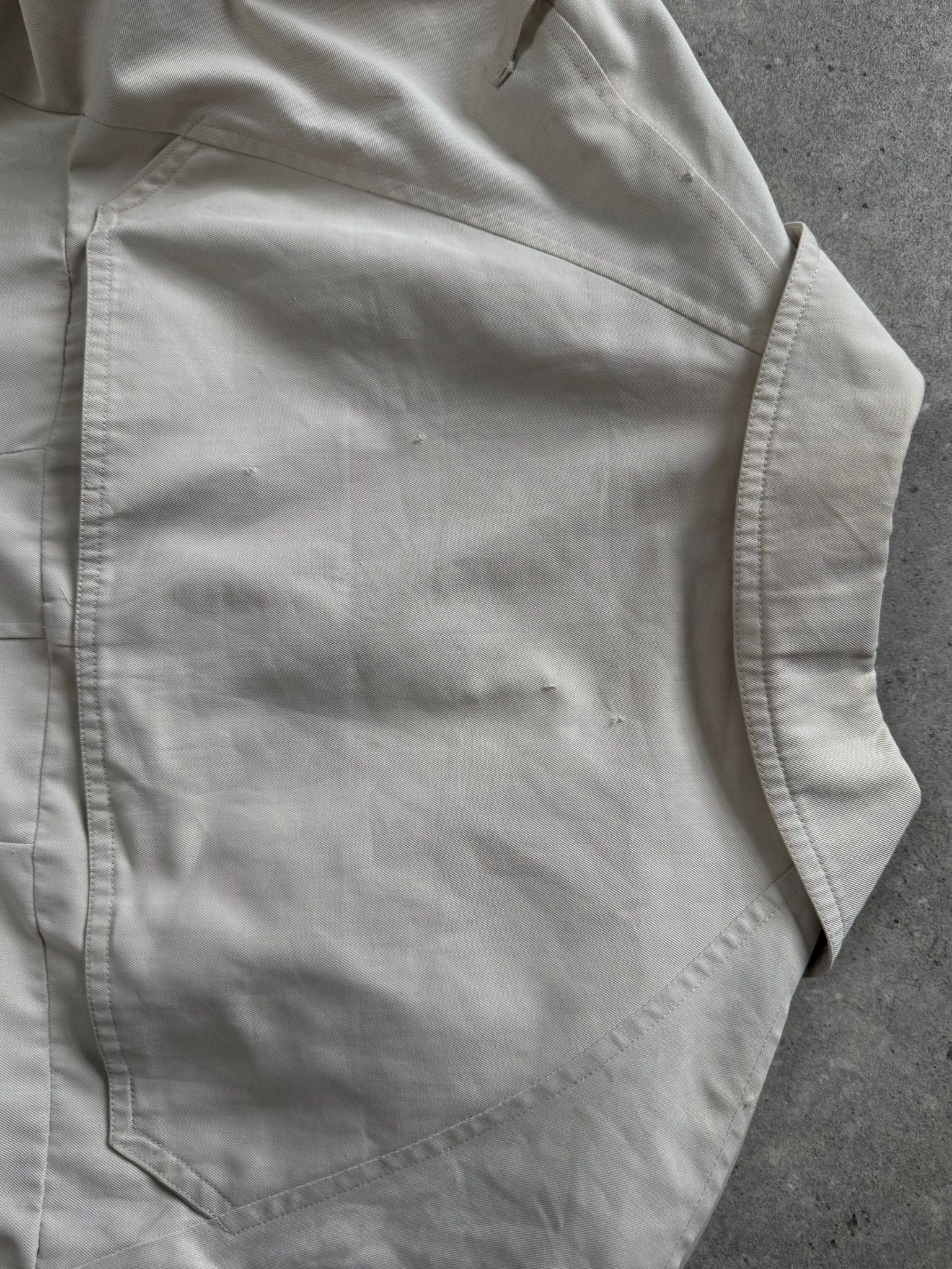 Burberry 1990s cotton double-breasted trench coat in beige, displayed on a hanger with classic design and belt detail.