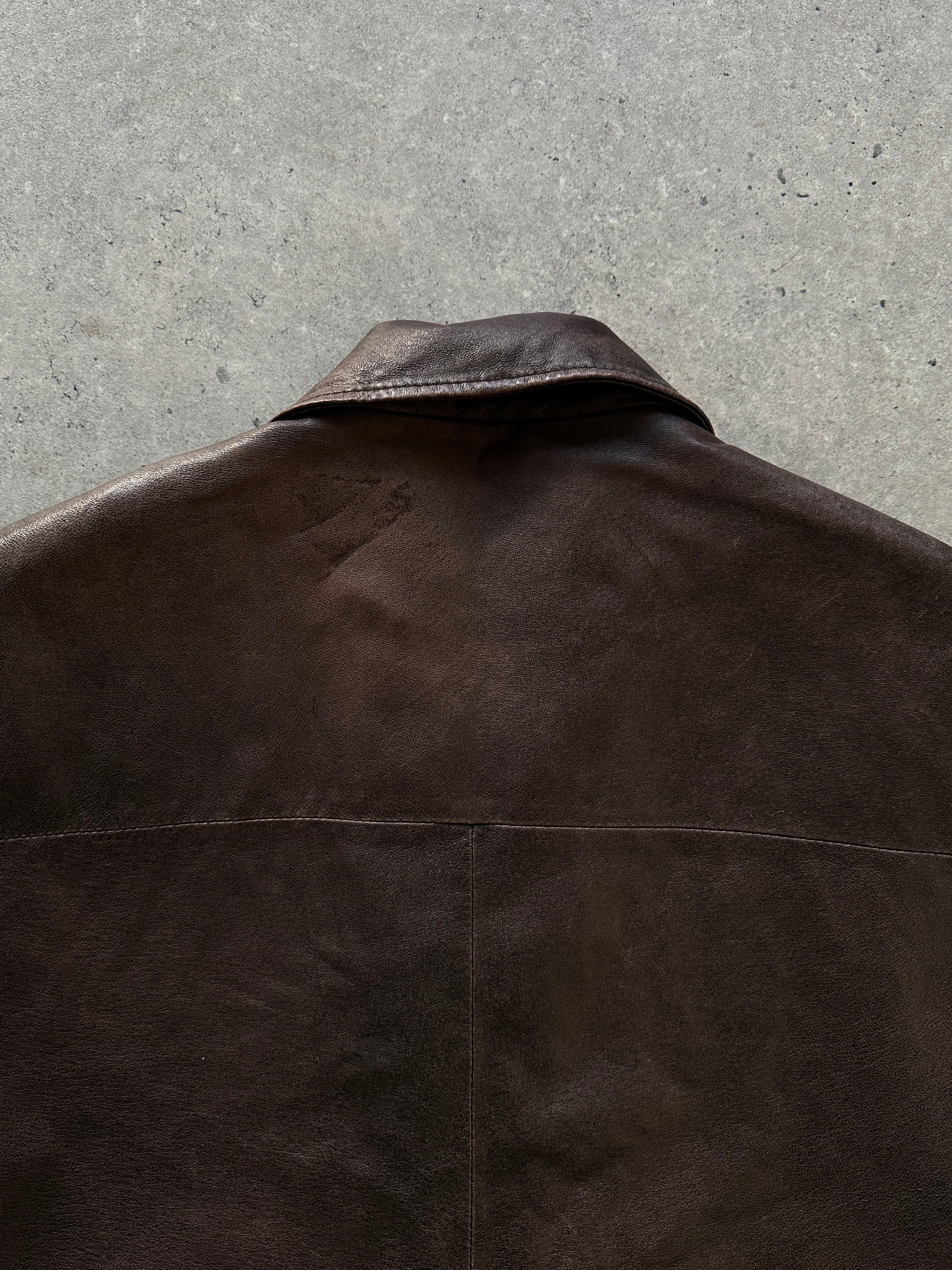 Vintage distressed leather jacket in size M/L, showcasing rugged, worn-in style with detailed stitching and classic collar.
