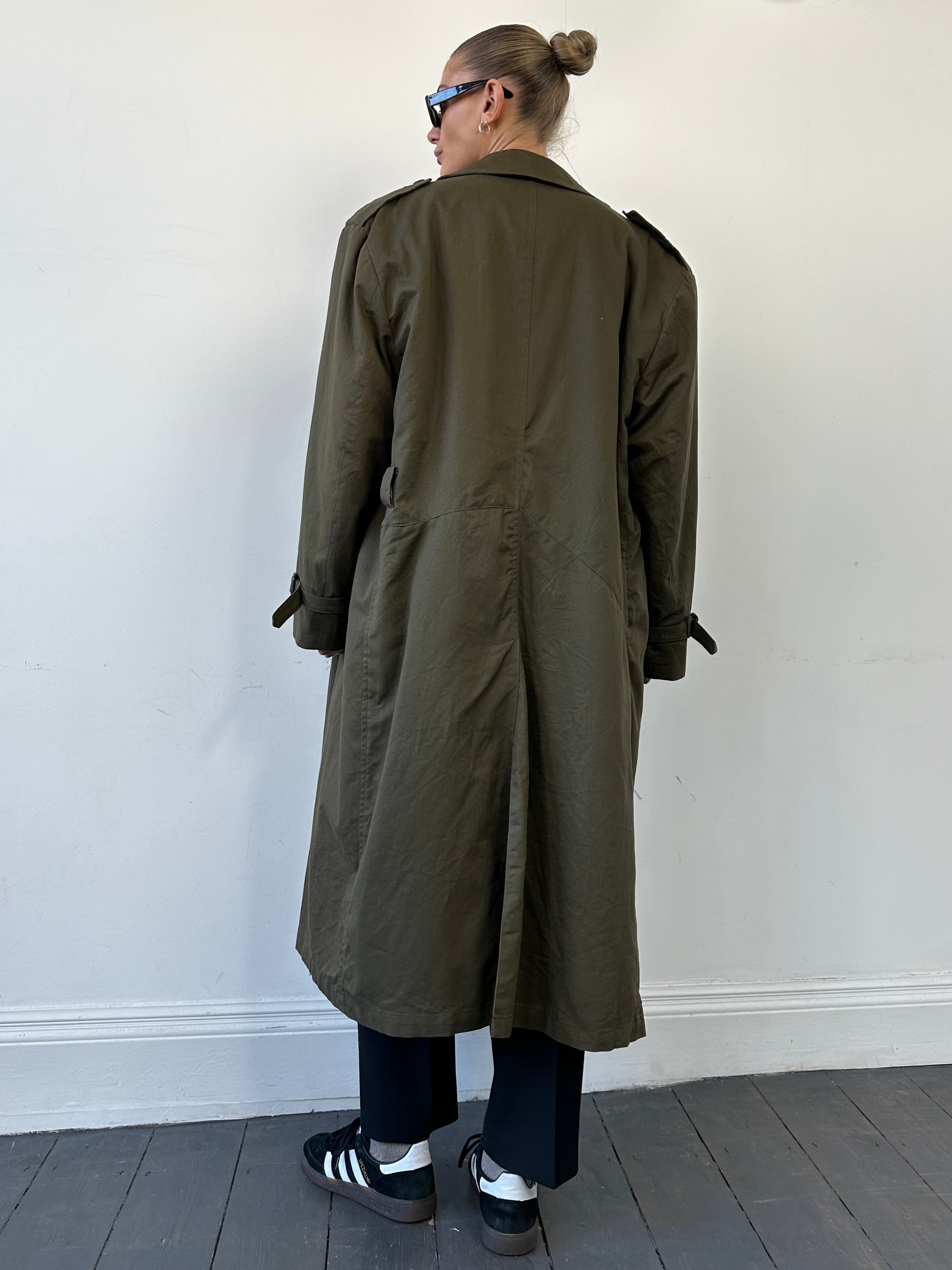 Christian Dior XL cotton double-breasted trench coat hanging on a wooden hanger, showcasing classic design and neutral color.