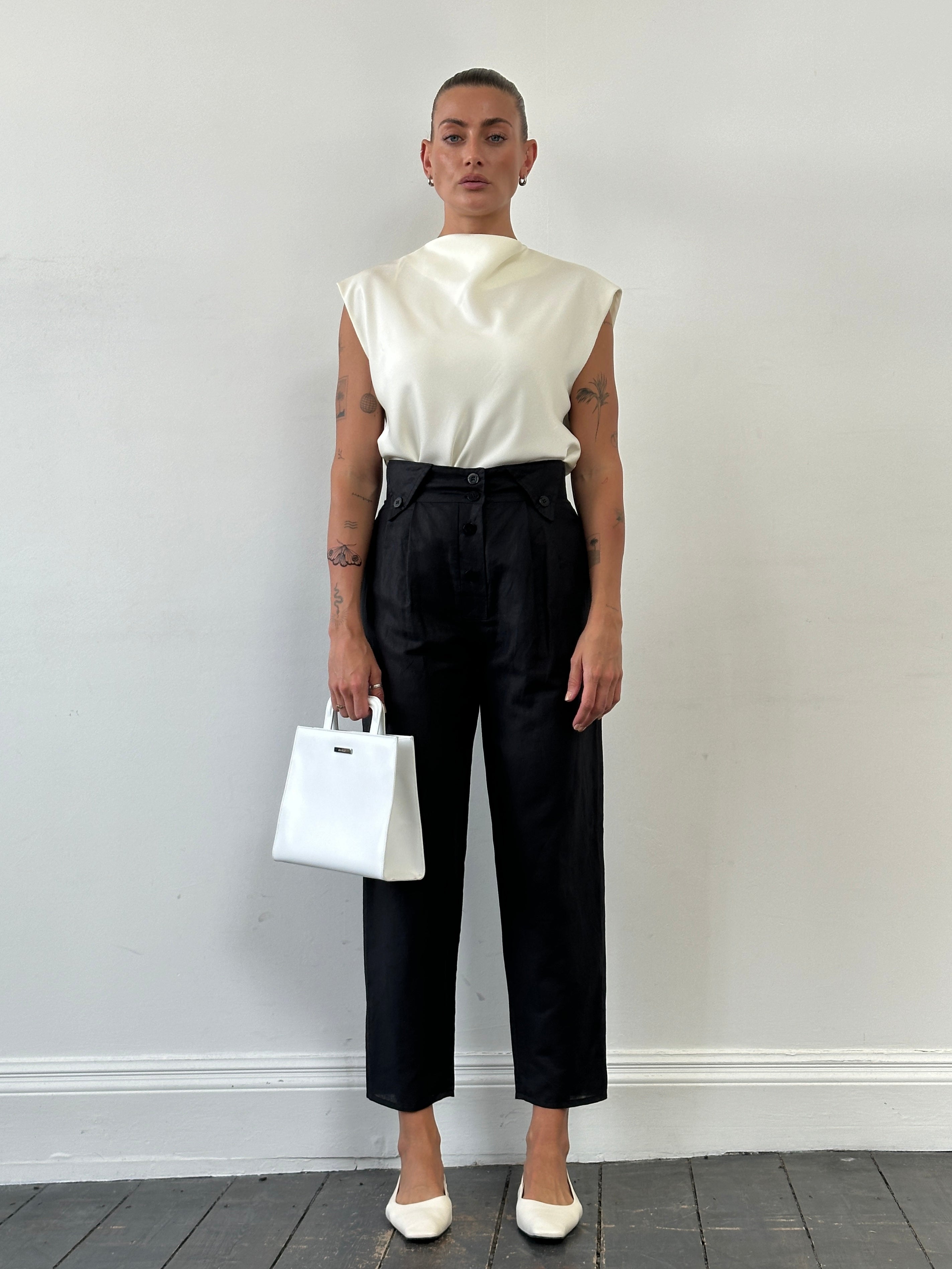 Vintage high waisted tapered trousers with a classic fit, shown in a neutral fabric with belt loops and side pockets.