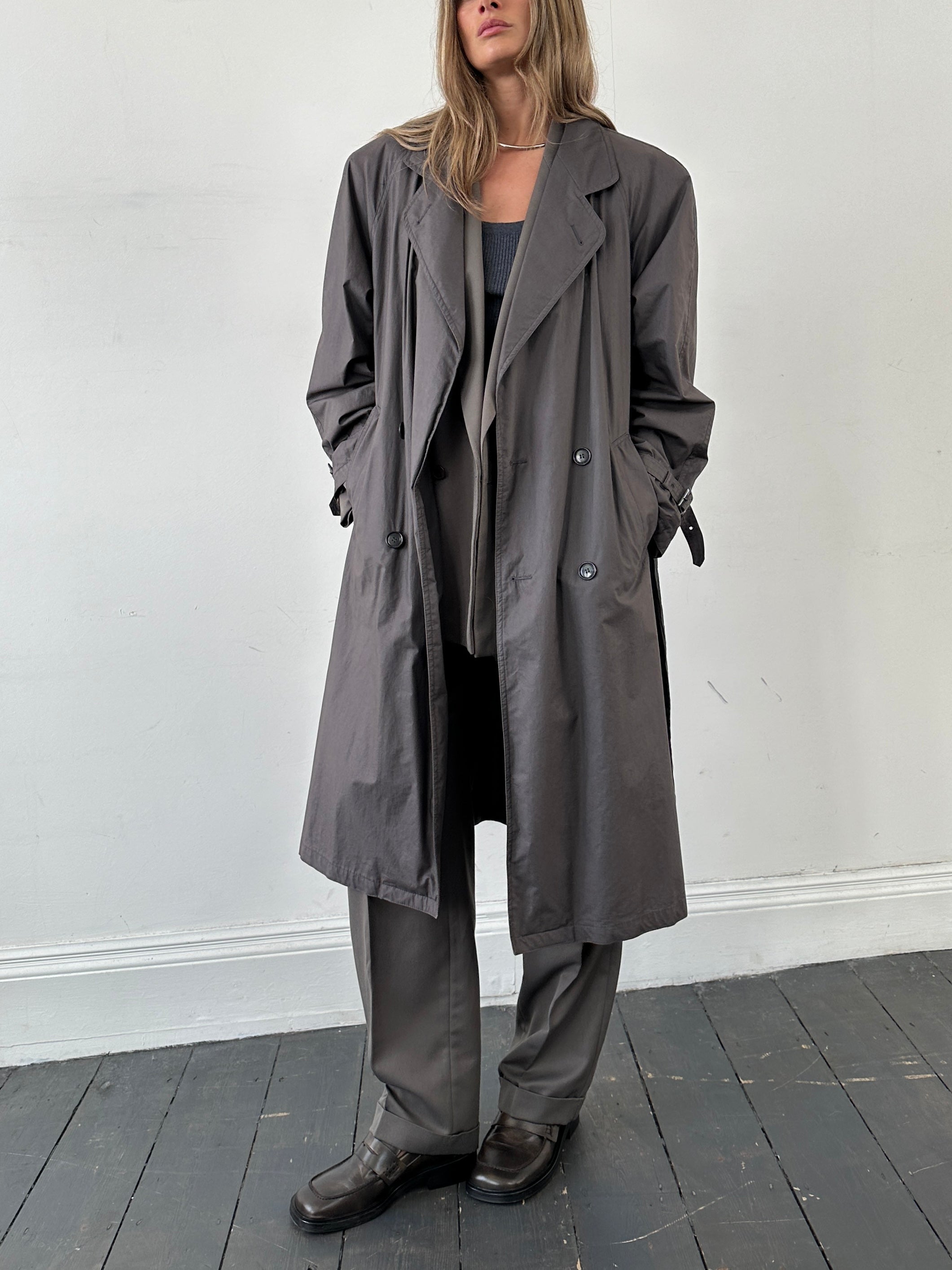Vintage double-breasted unlined belted trench coat in size L, featuring classic design and neutral color, displayed on a hanger.