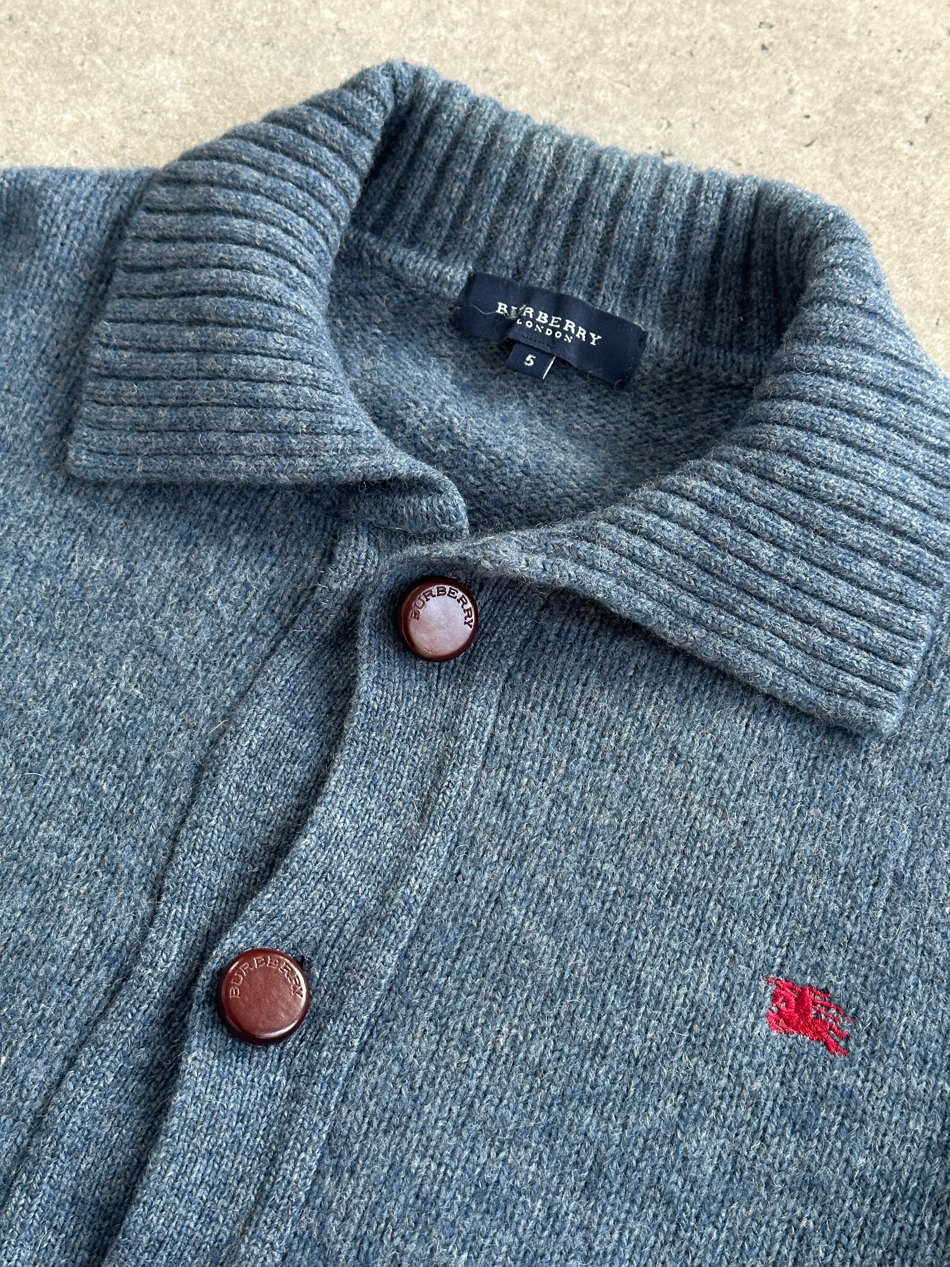 Burberry London wool knitted logo cardigan in M/L displayed on a hanger, showcasing its classic design and textured knit fabric.
