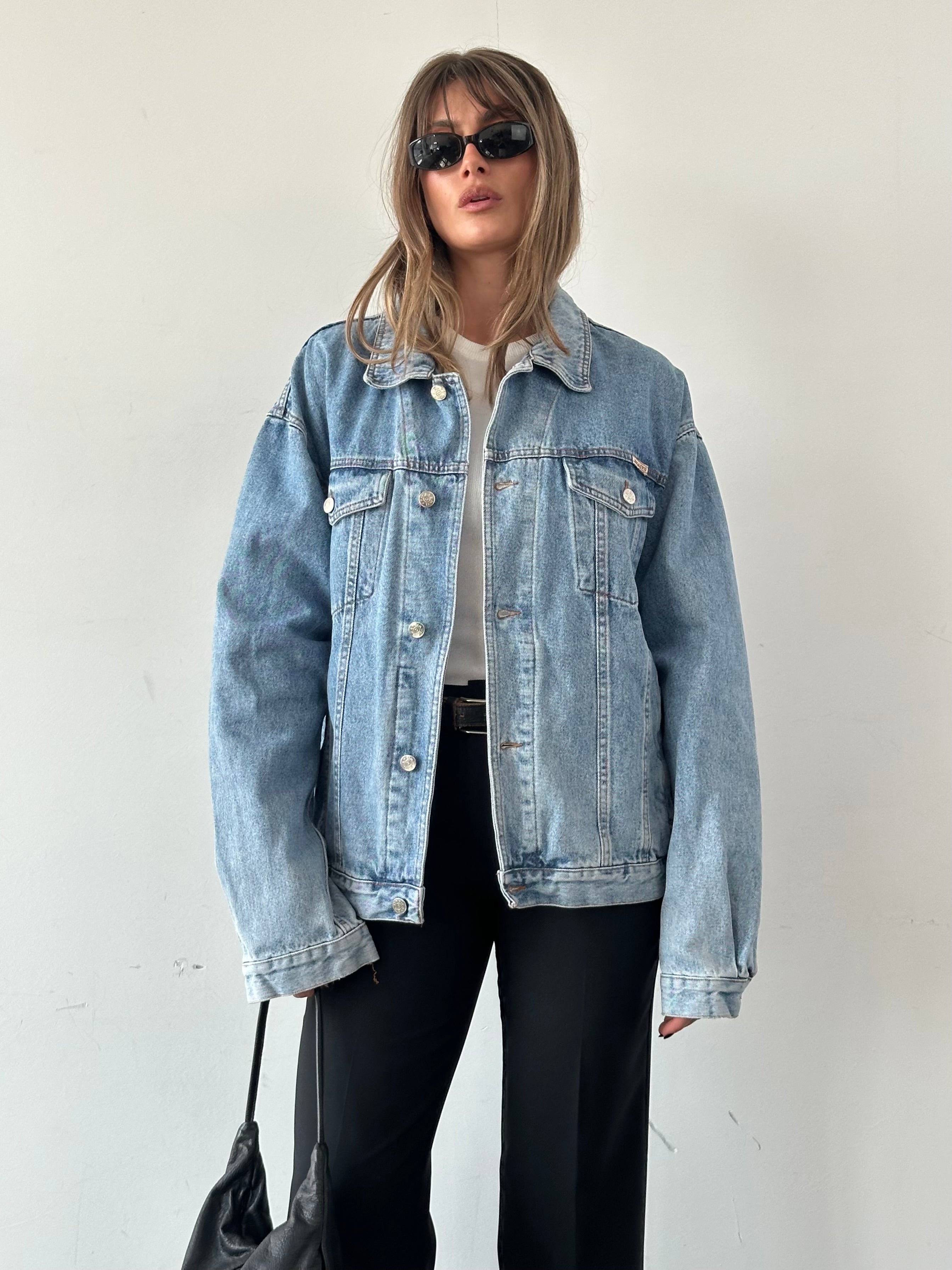 Vintage oversized denim jacket in XL, featuring classic design and distressed details, displayed on a hanger.