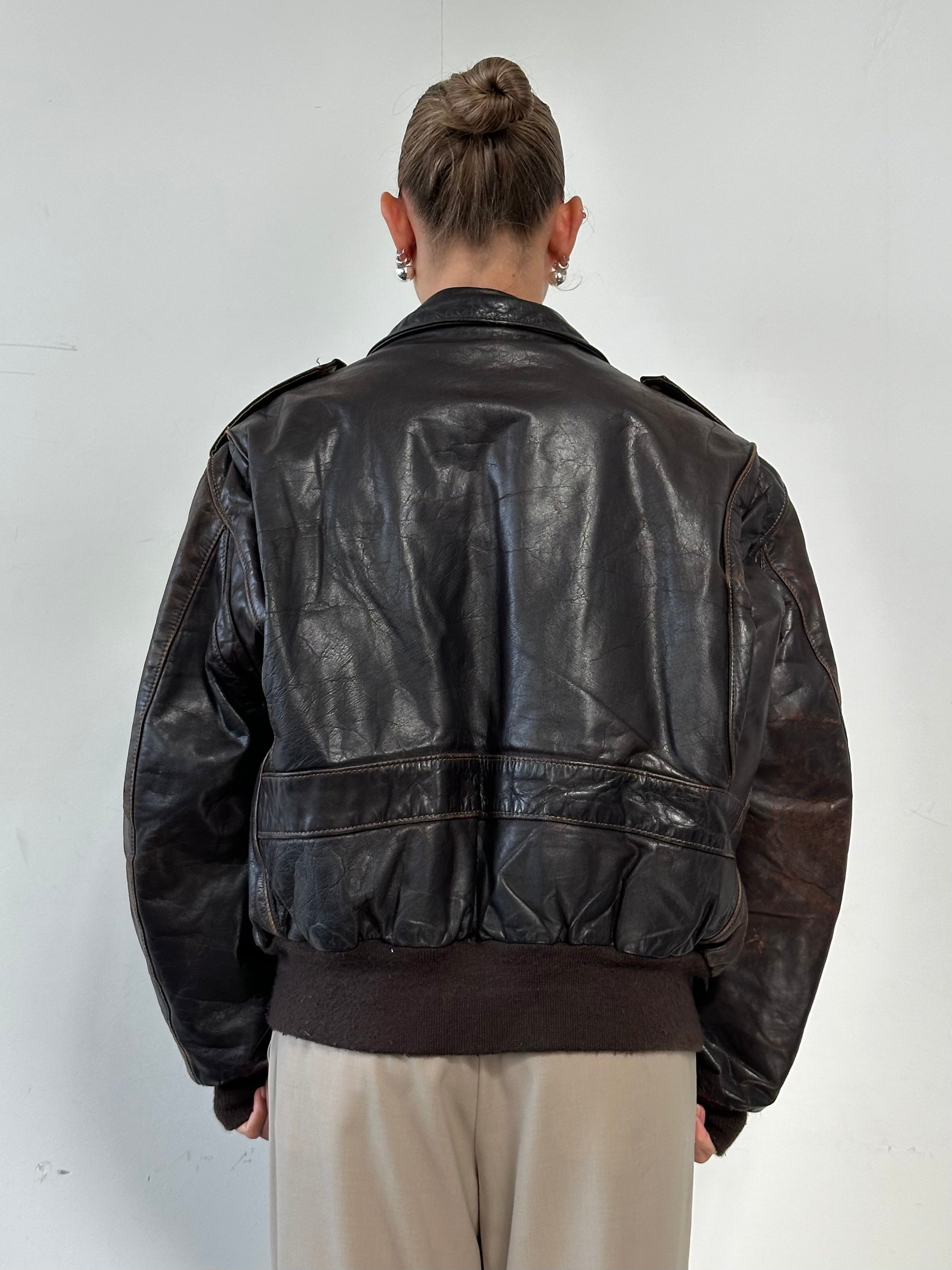 Schott NYC distressed leather bomber jacket in size L/XL, featuring a rugged design and classic fit with zip closure and ribbed cuffs.