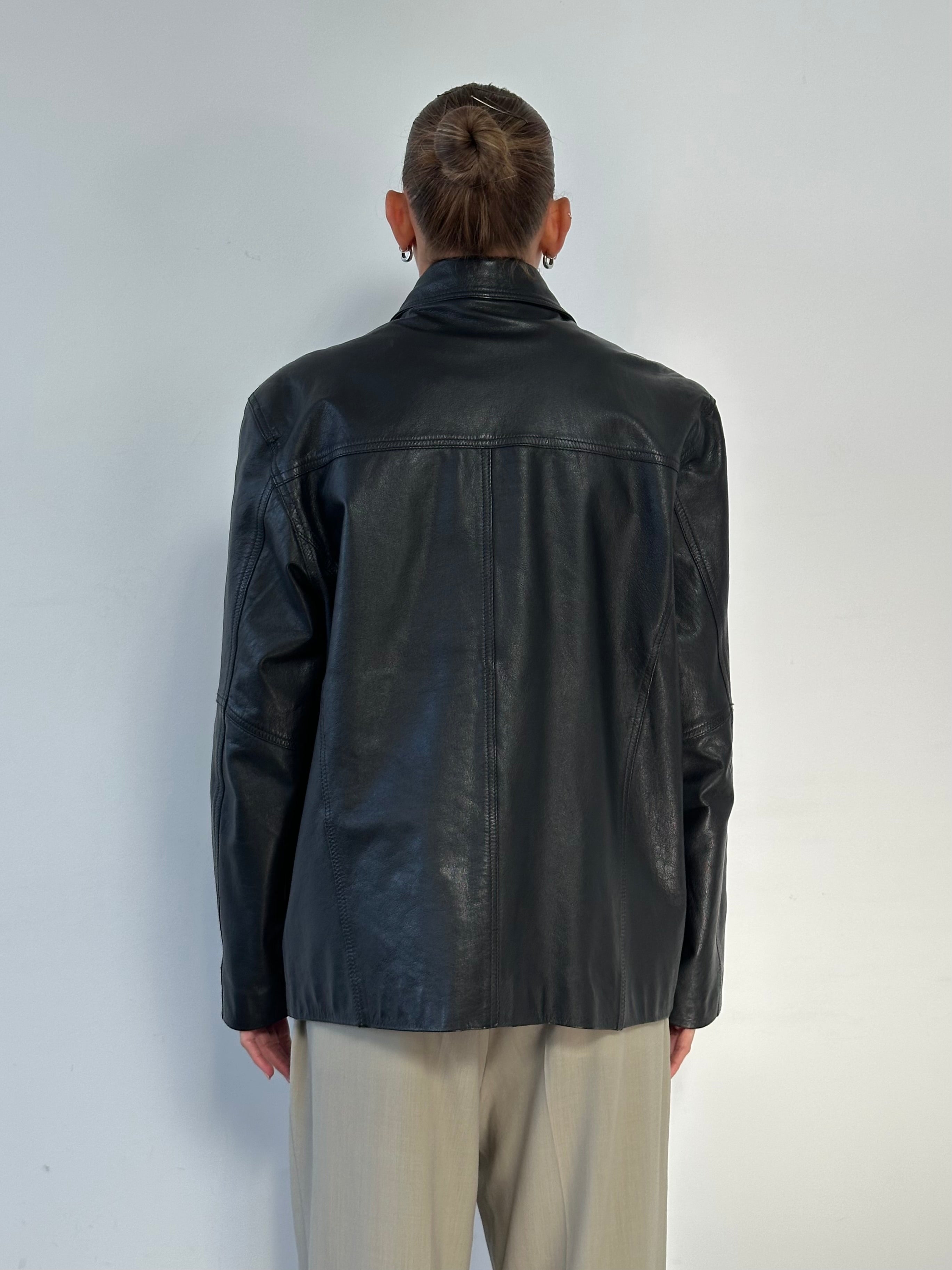 Vintage minimal leather jacket in size M/L, featuring sleek design and classic style, shown on a hanger.