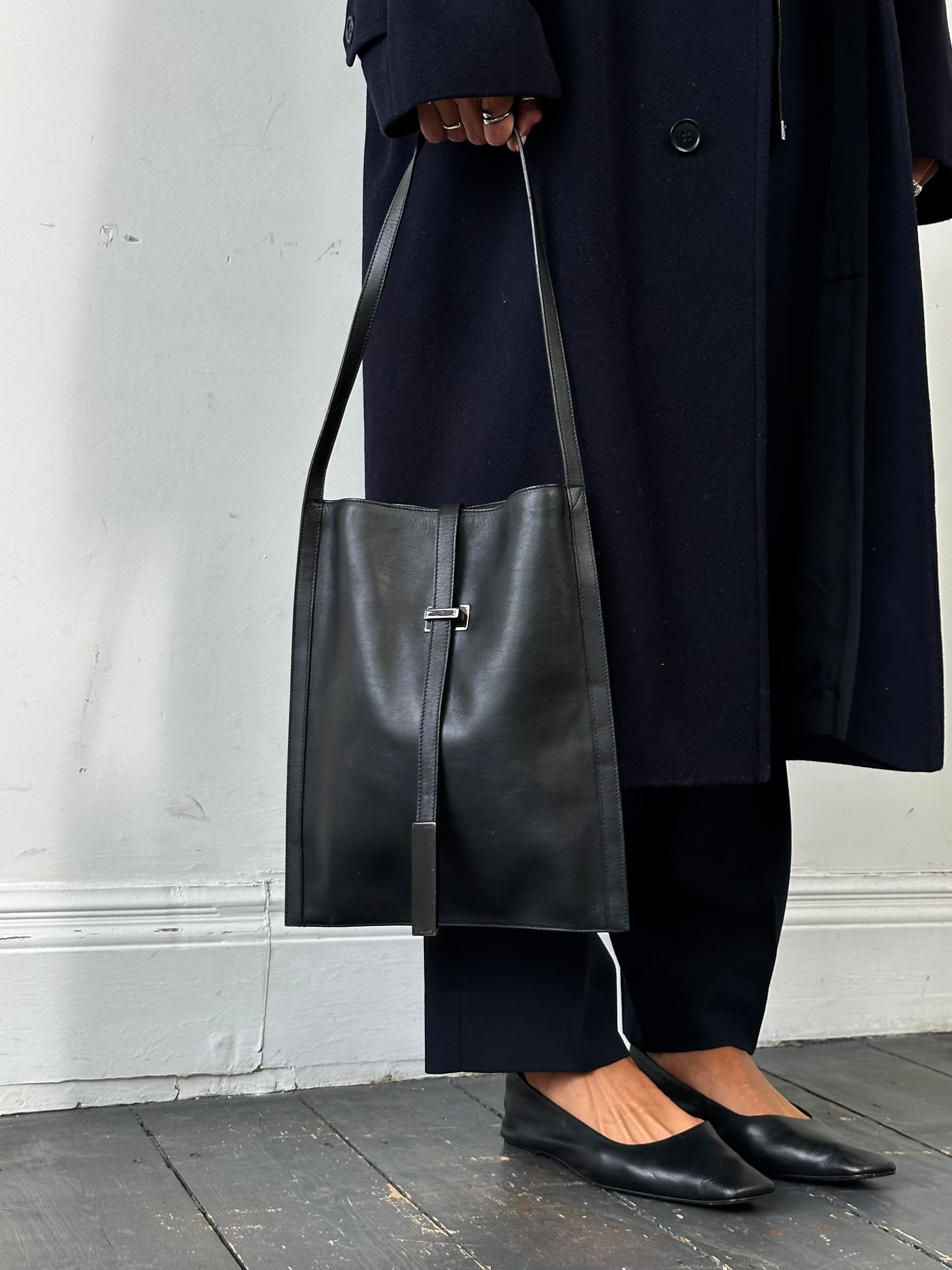 Gucci minimal rectangle leather bag with sleek design and adjustable strap, showcasing smooth black leather and subtle branding.