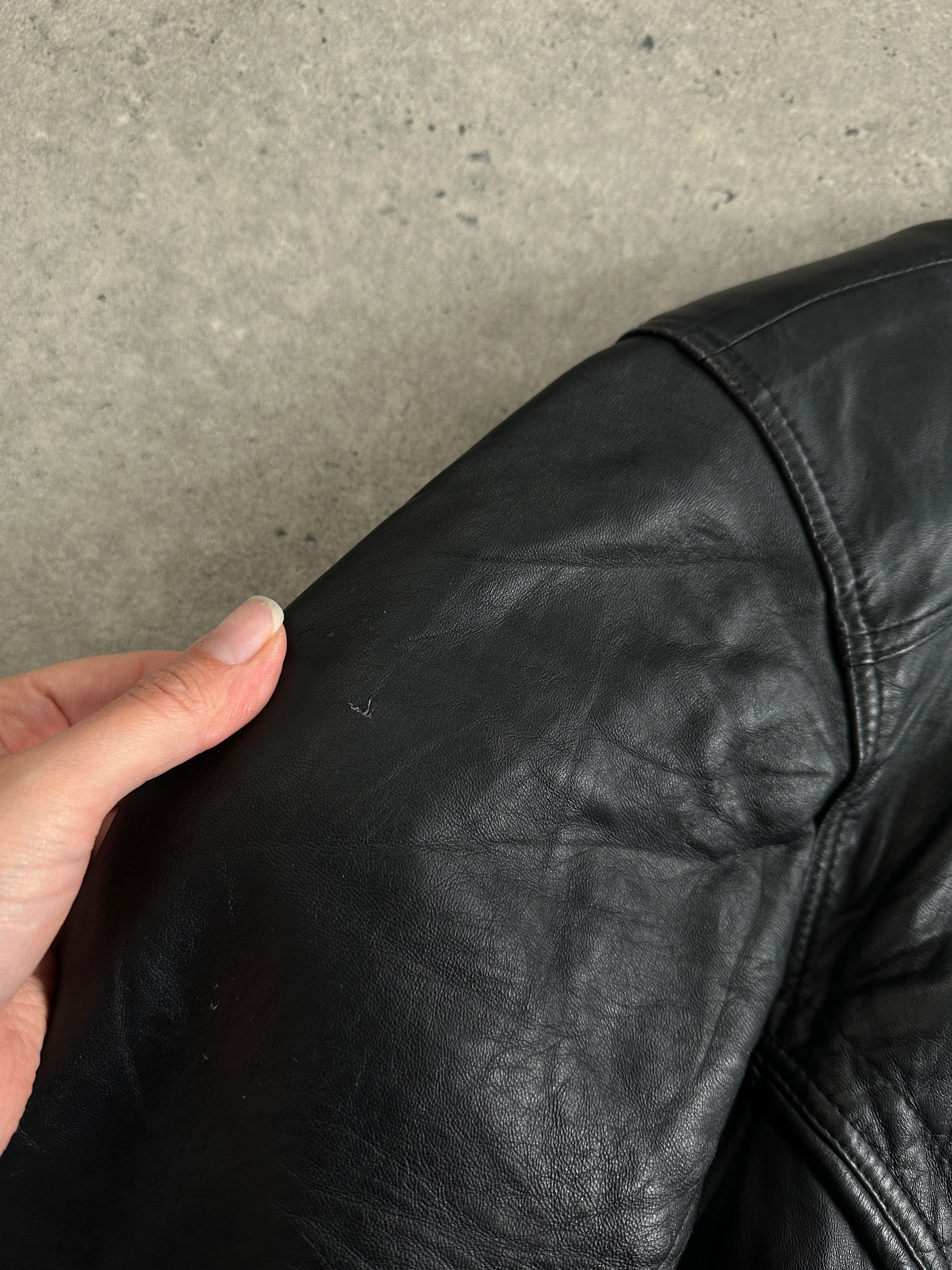 Vintage leather bomber jacket in XL size, featuring classic design with zip closure and ribbed cuffs, on a hanger against a neutral background.