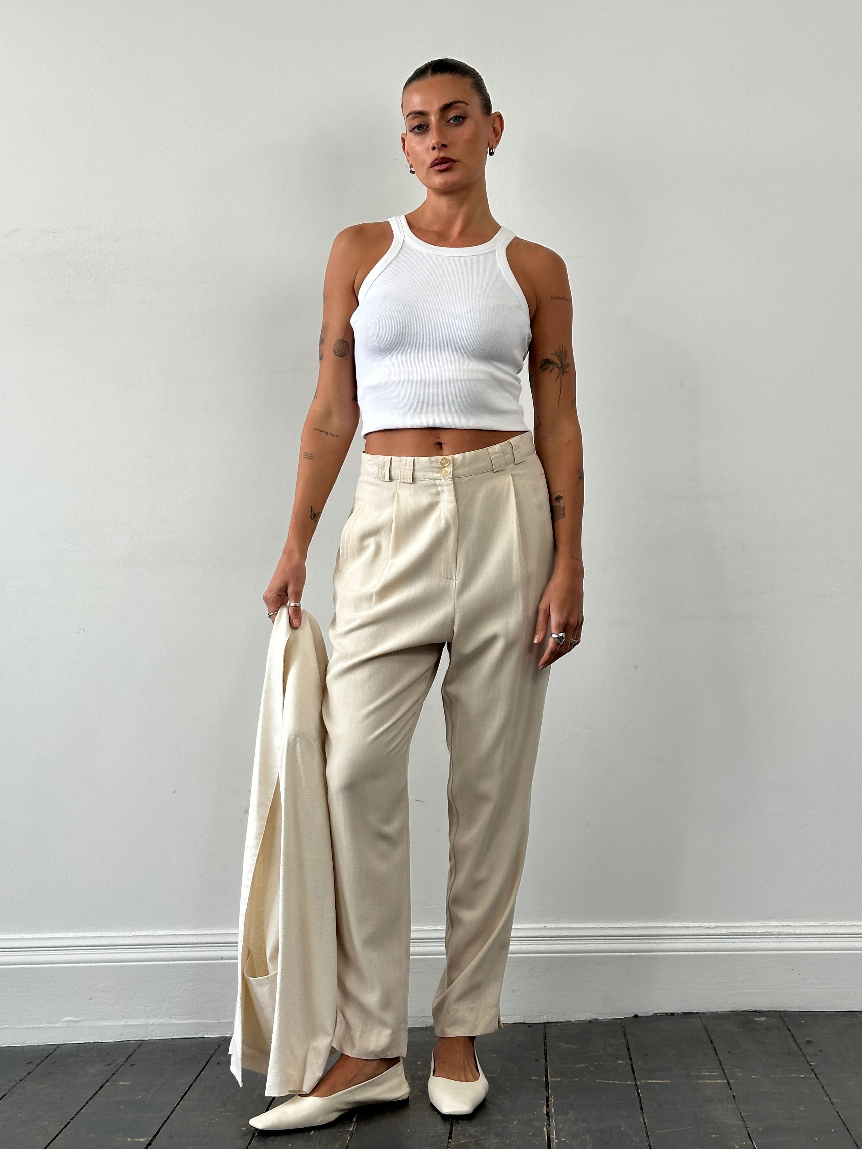 Vintage high waisted tailored pleated trousers in W28, featuring classic design and sharp pleats, on a neutral background.
