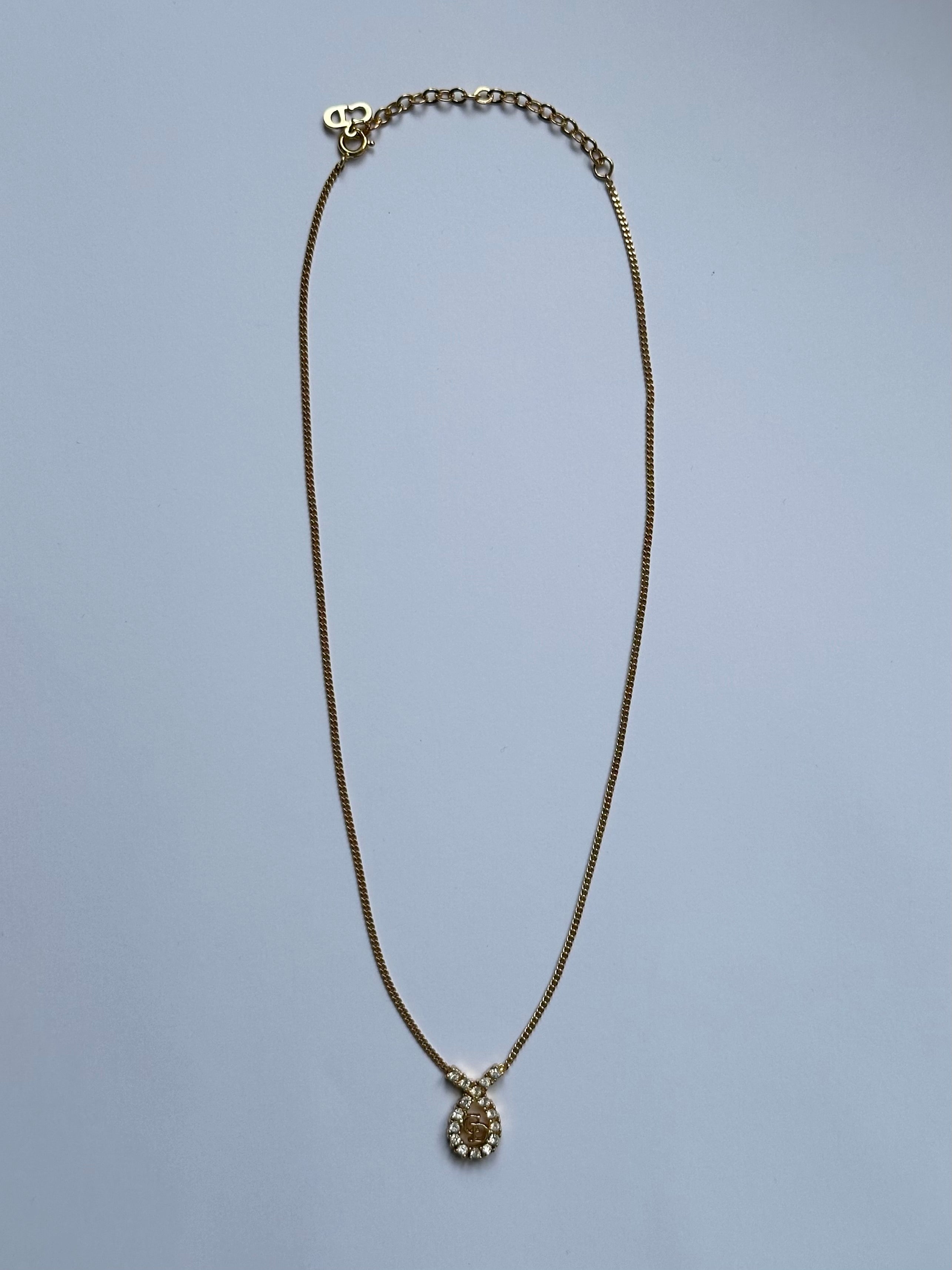 Christian Dior 16-inch gold plated rhinestone drop logo pendant necklace with intricate detailing and sparkling rhinestones.