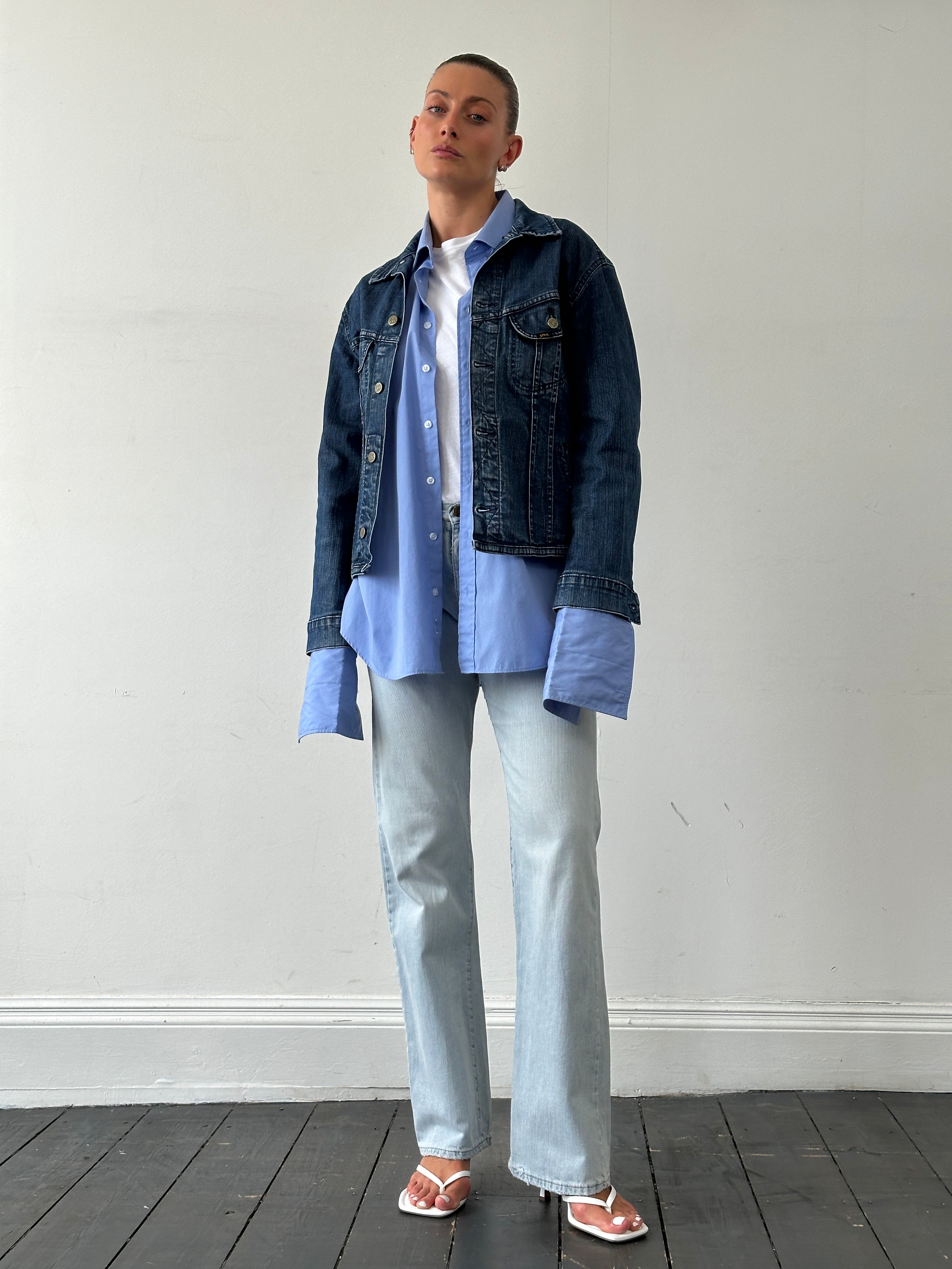 Lee cotton fitted denim jacket in size M, shown hanging on a hanger with classic blue denim fabric and button closure.