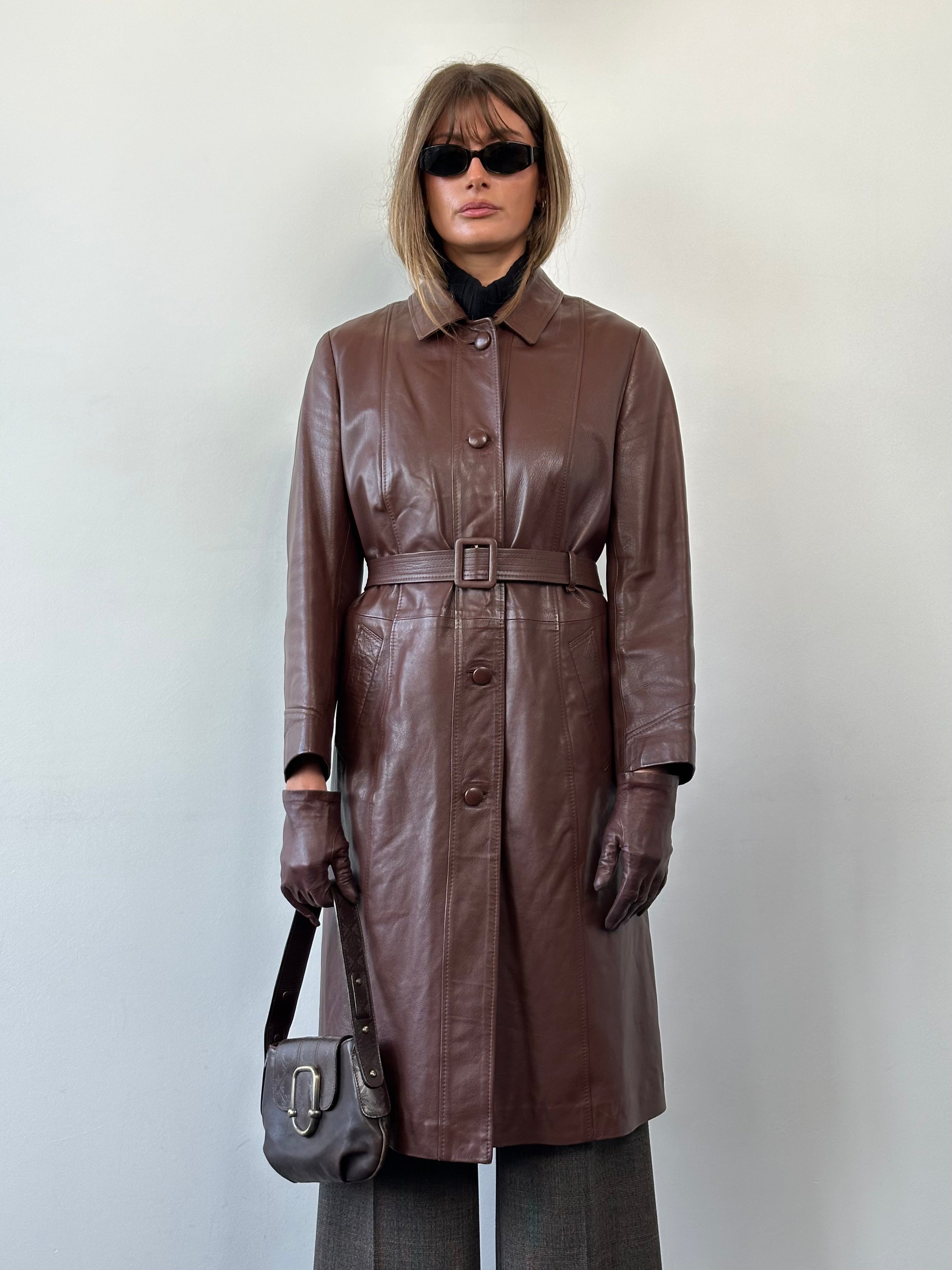 Vintage smooth leather belted trench coat, classic jacket in M/L size with stylish design and timeless appeal.