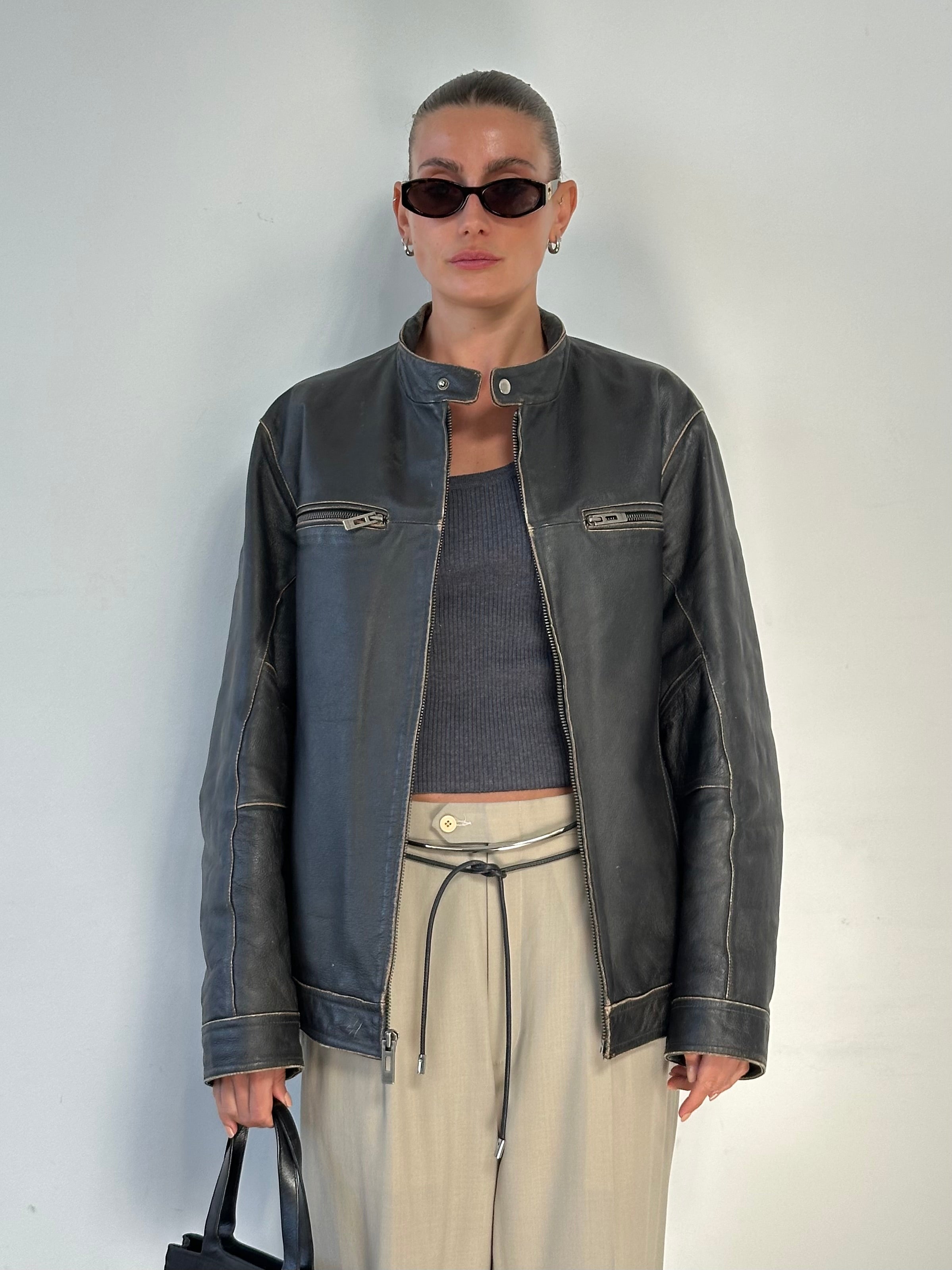 Guess distressed moto leather jacket in size large shown on a hanger, featuring a rugged design with silver hardware details.