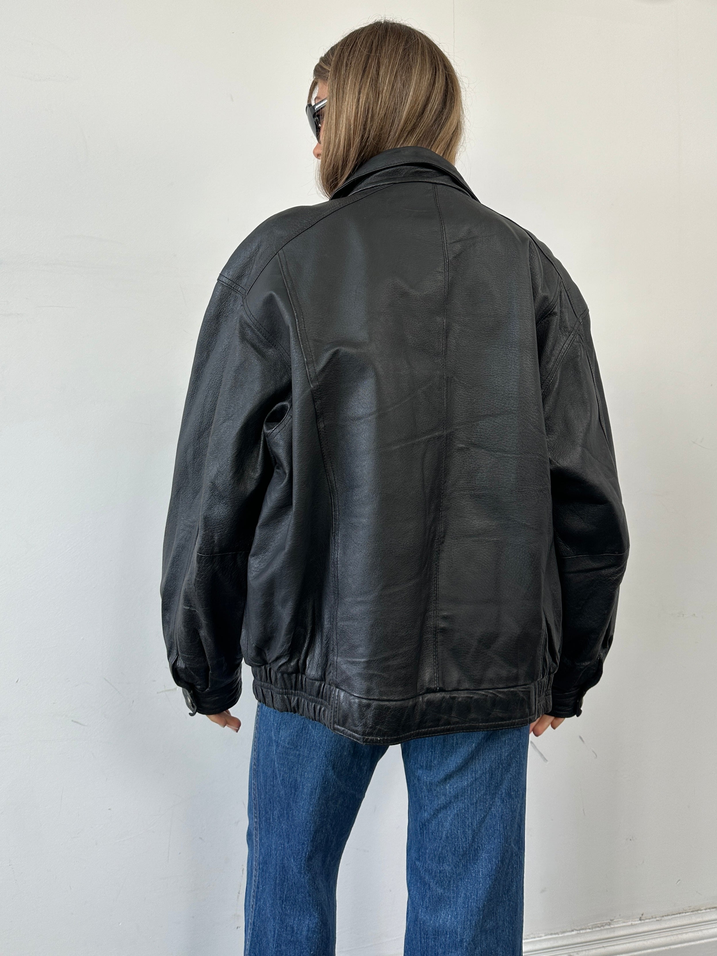 Vintage leather bomber jacket in XL size, featuring classic design and rich brown color, displayed on a hanger.