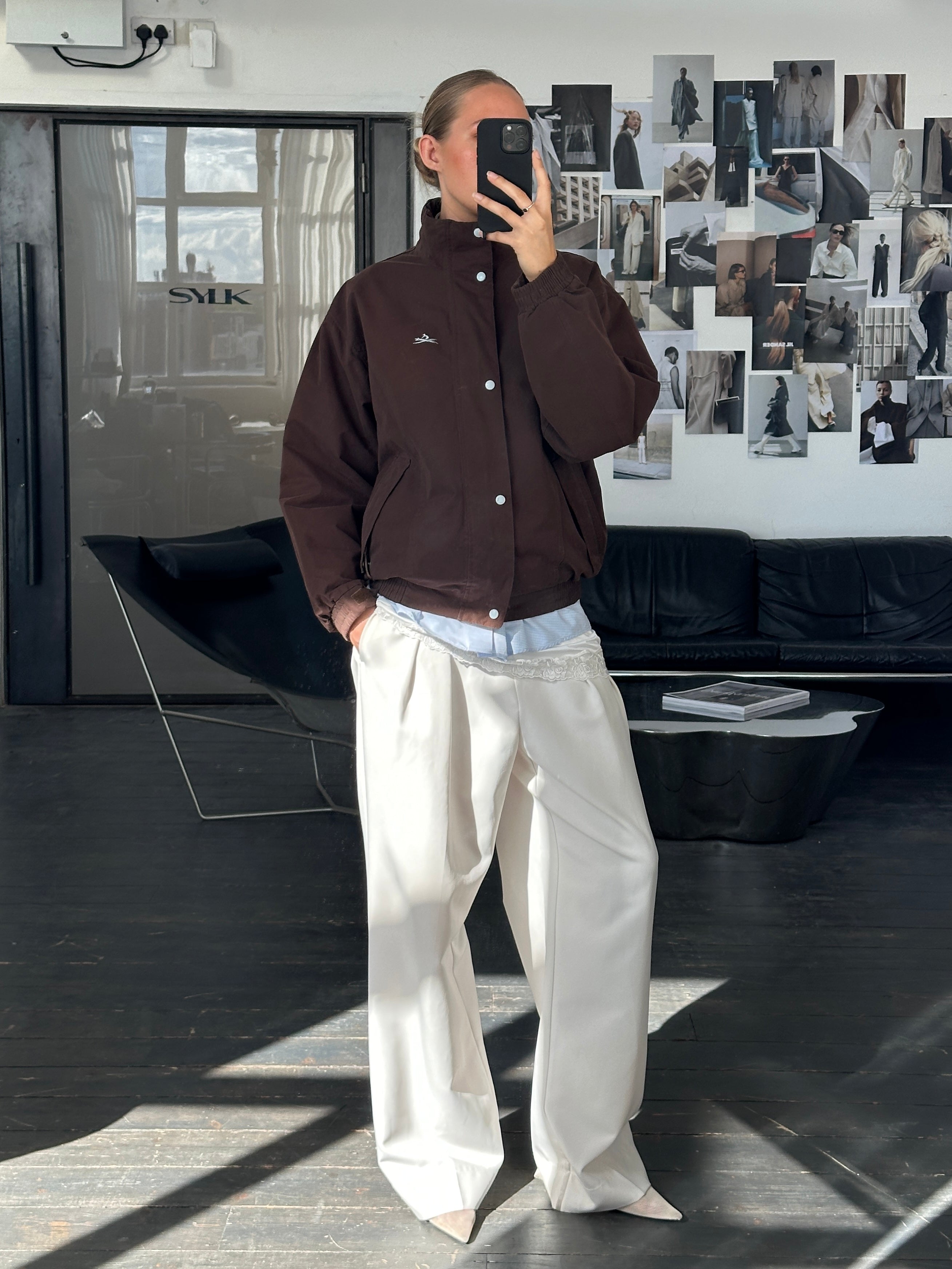 Vintage 2000s double zip boxy bomber jacket in black with ribbed cuffs and collar, displayed on a hanger.