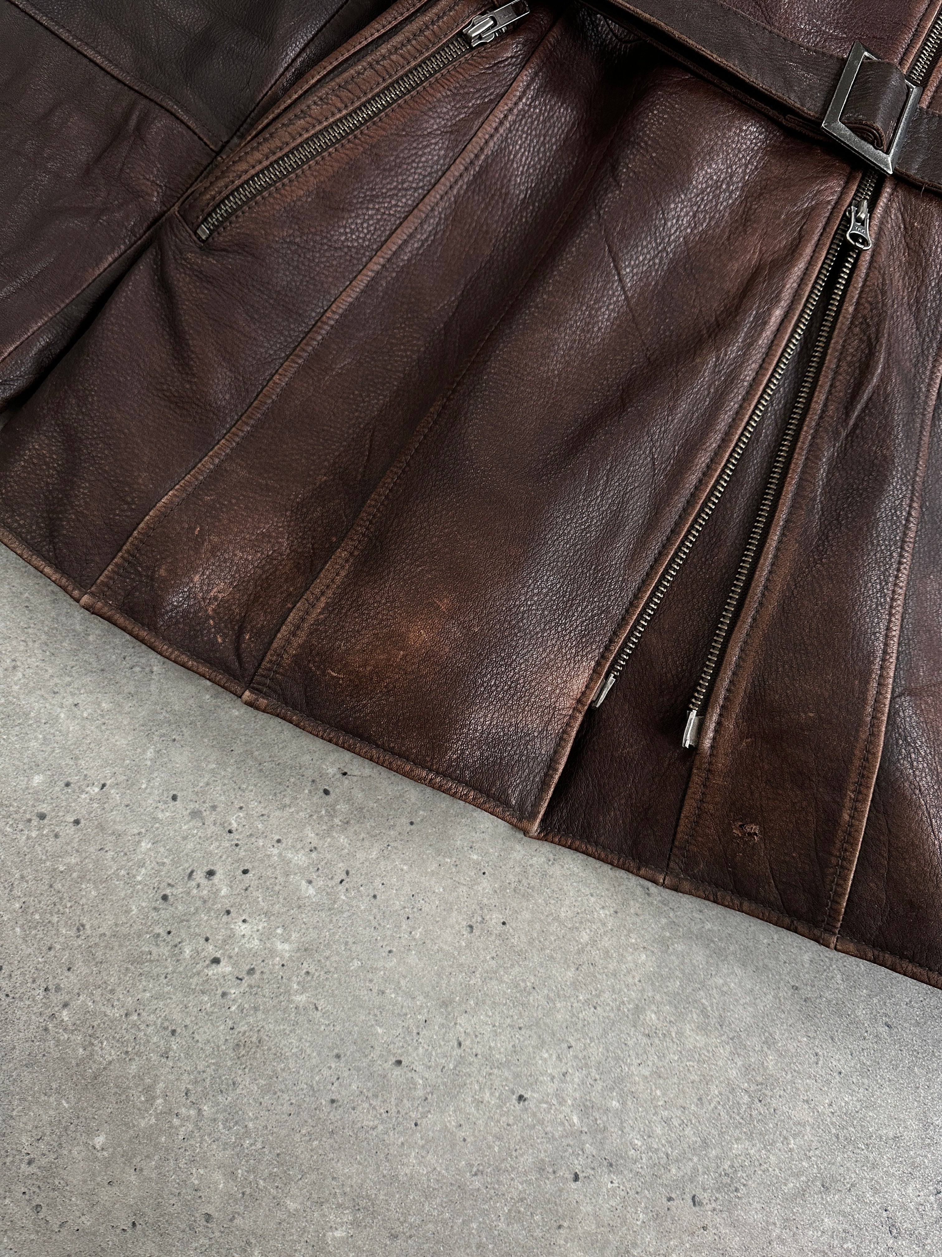 Vintage 1990s aged leather jacket with double zip and belt, featuring classic style and rugged texture.