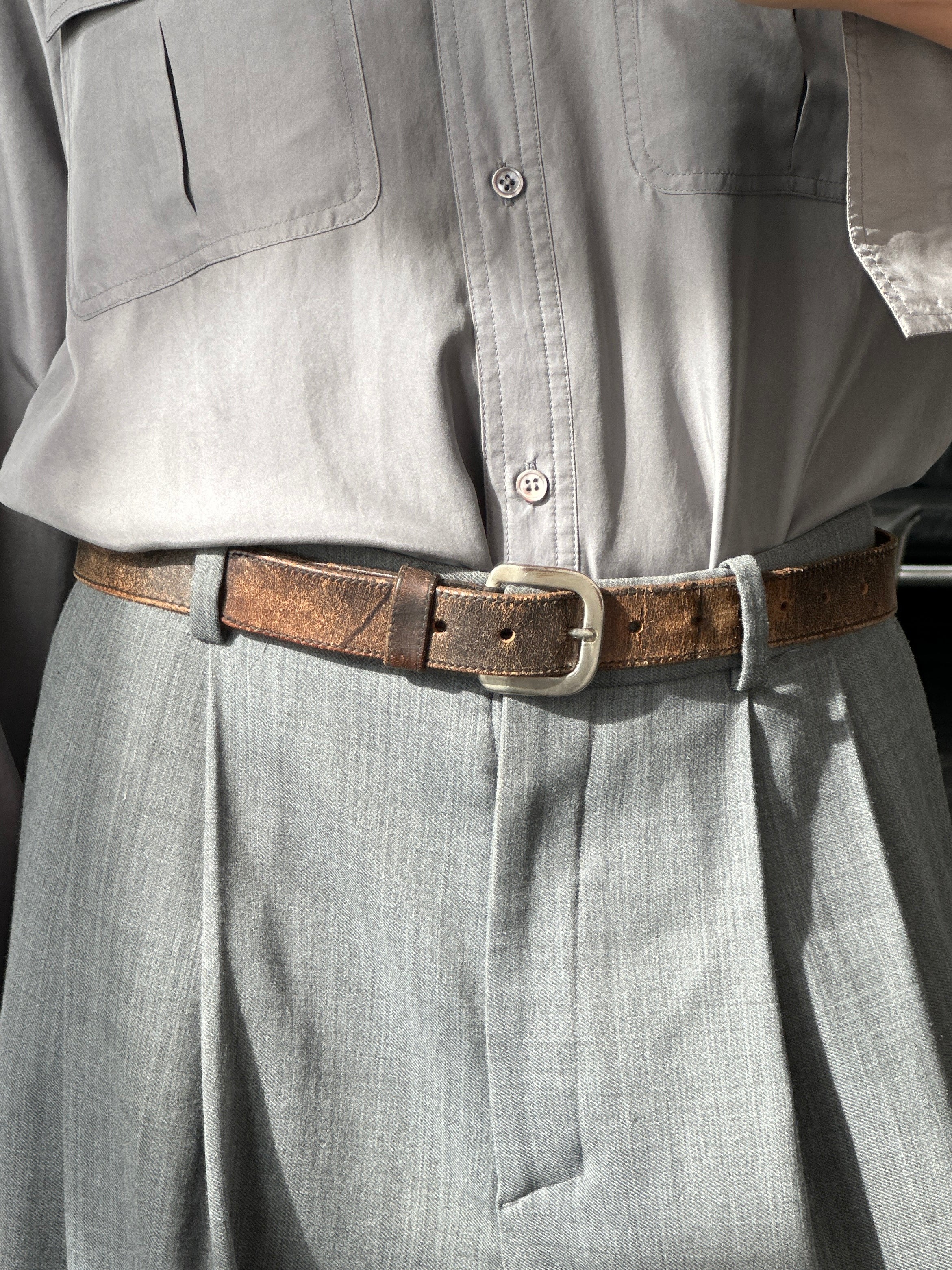 Vintage 1980s distressed leather belt in W27-35 with rugged, worn look, featuring a classic buckle and aged leather finish.