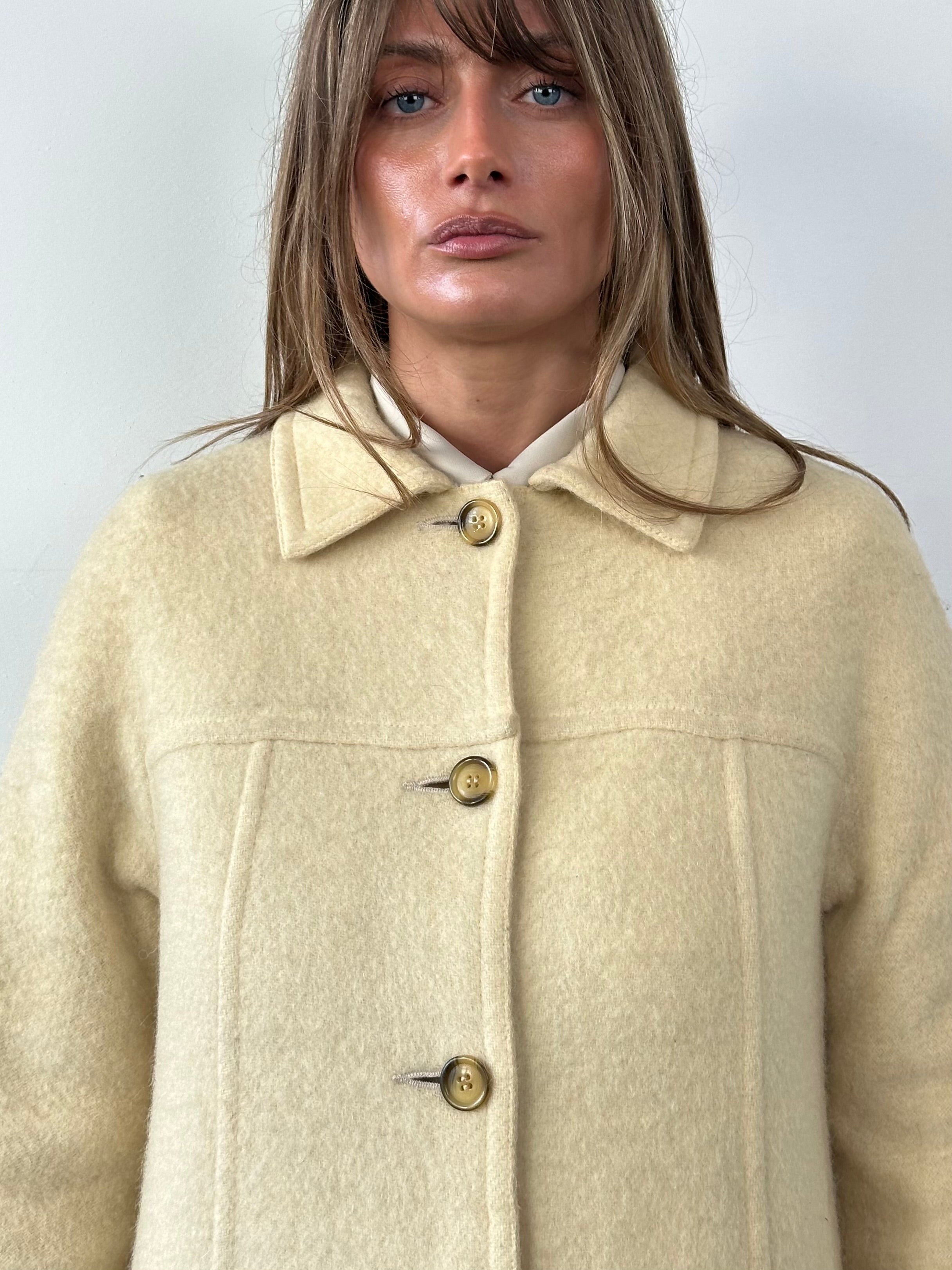 Marella 80s wool double-faced single-breasted coat in neutral tones, shown hanging on a wooden hanger with a blurred background.