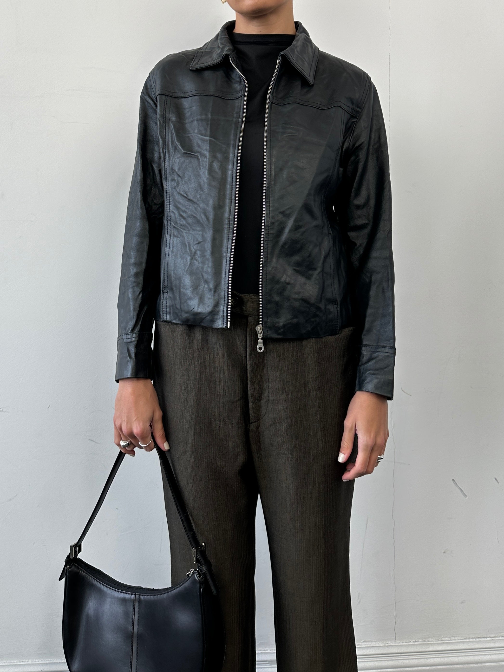 Vintage minimal zip-up leather jacket in size small, showcasing sleek black leather with silver zipper details.
