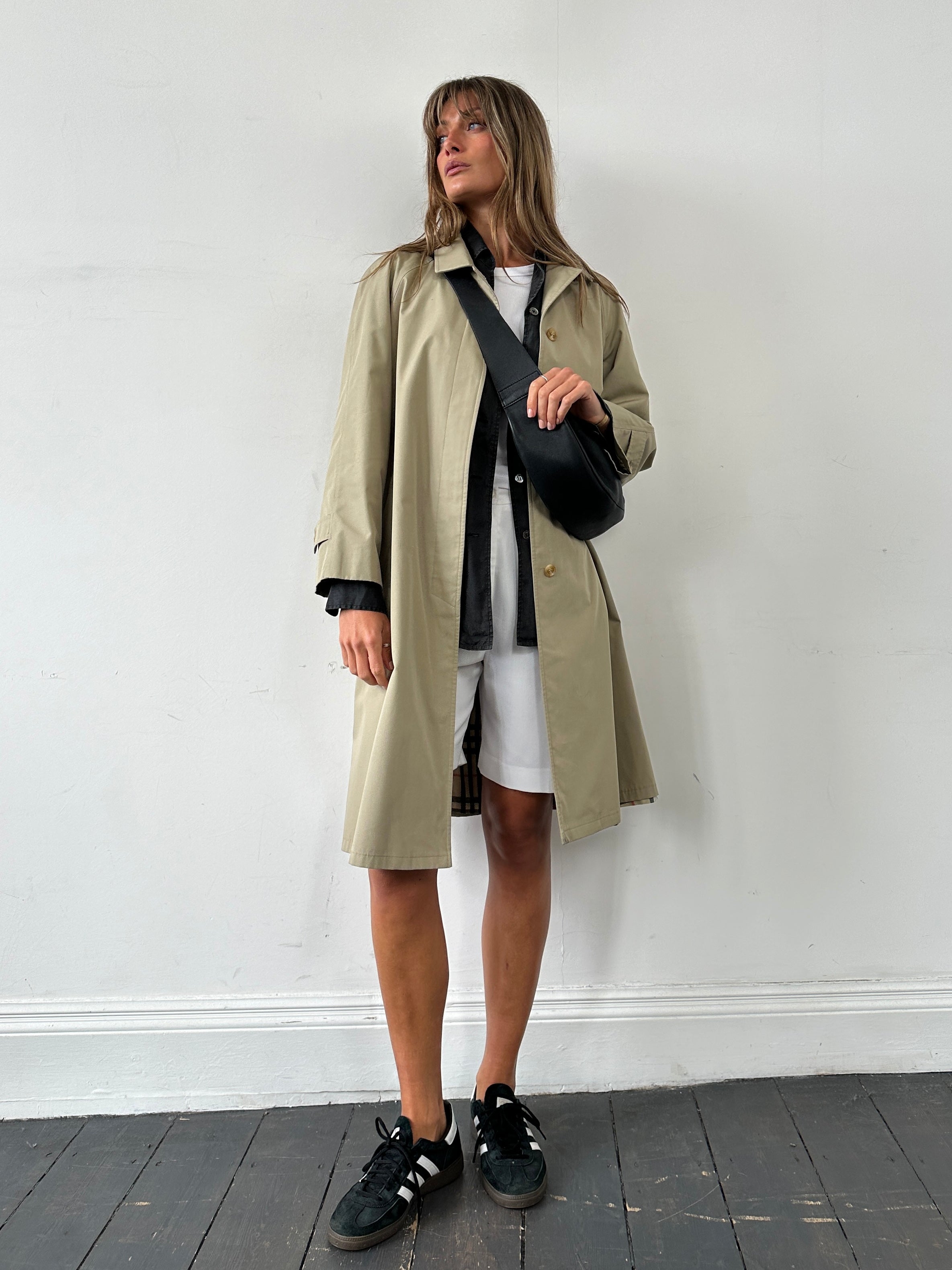 Vintage showerproof belted trench coat in size M, featuring classic design and durable fabric, shown on a hanger.