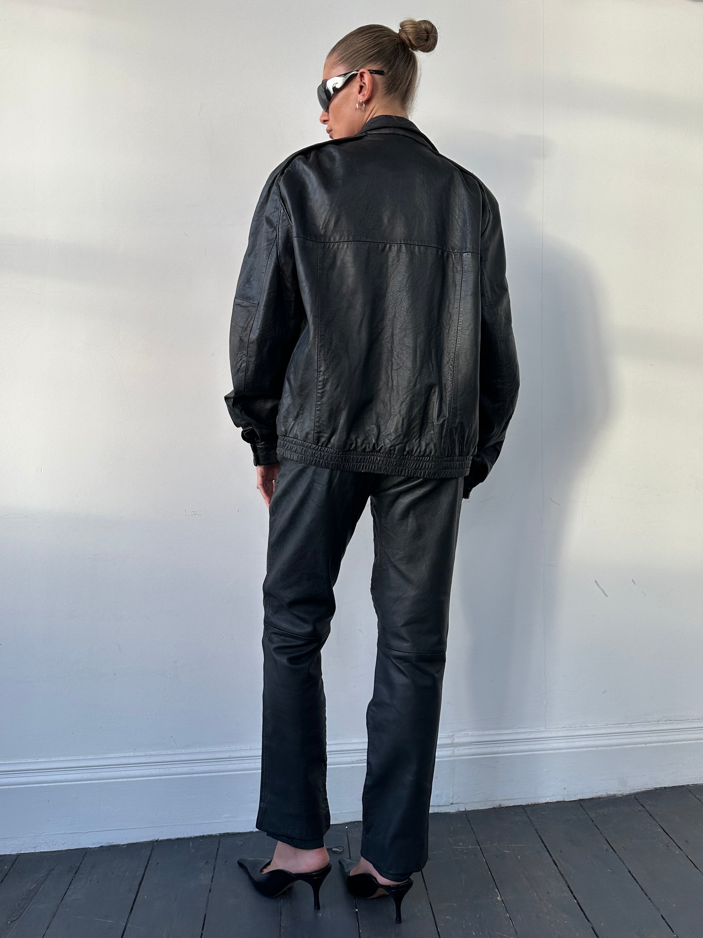 Vintage high waisted straight leg leather trousers in W28, showing the fit and texture of the classic leather material.