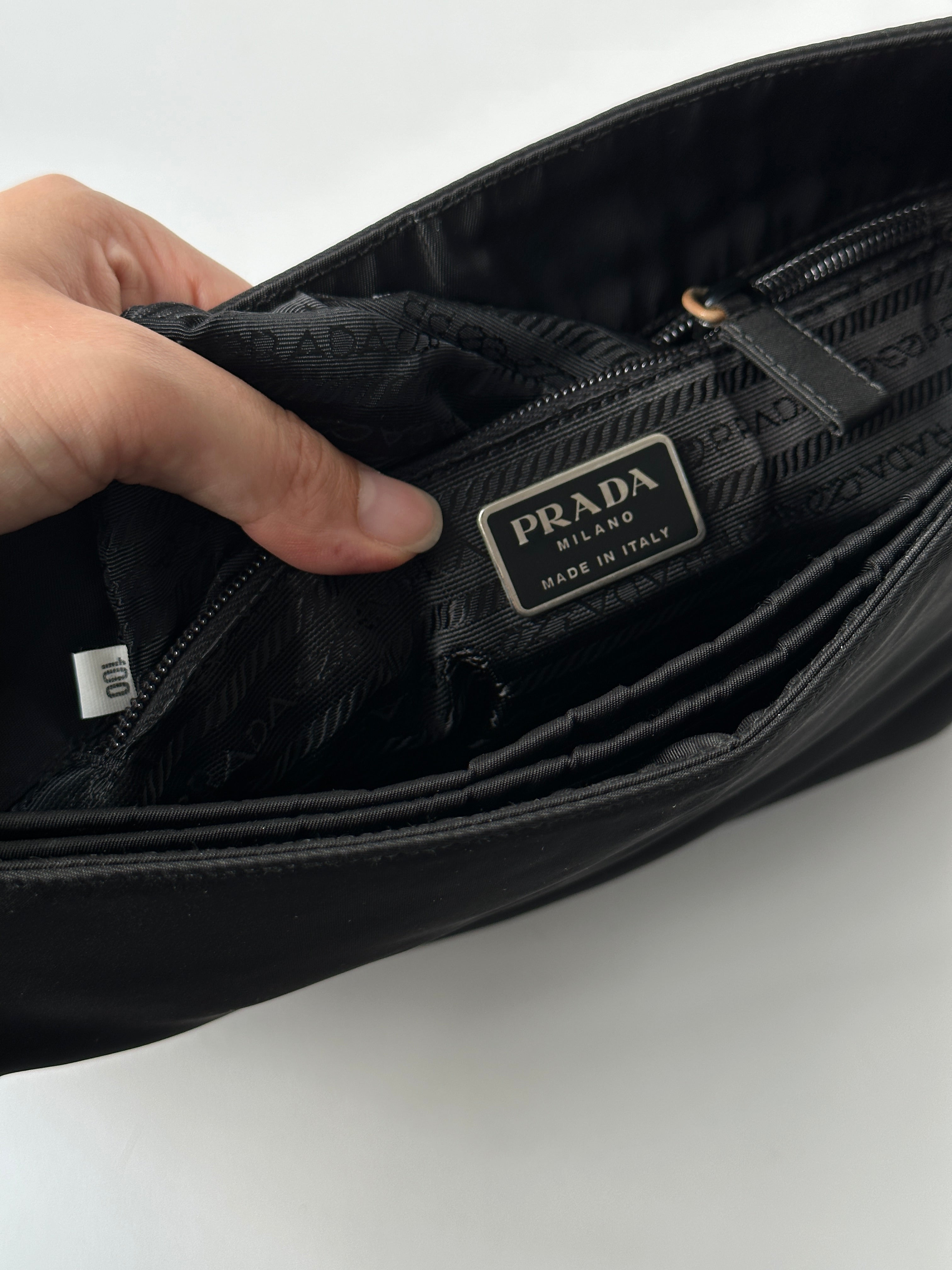 Prada nylon shoulder bag with metal handle and sleek design, featuring a spacious interior and contemporary style.