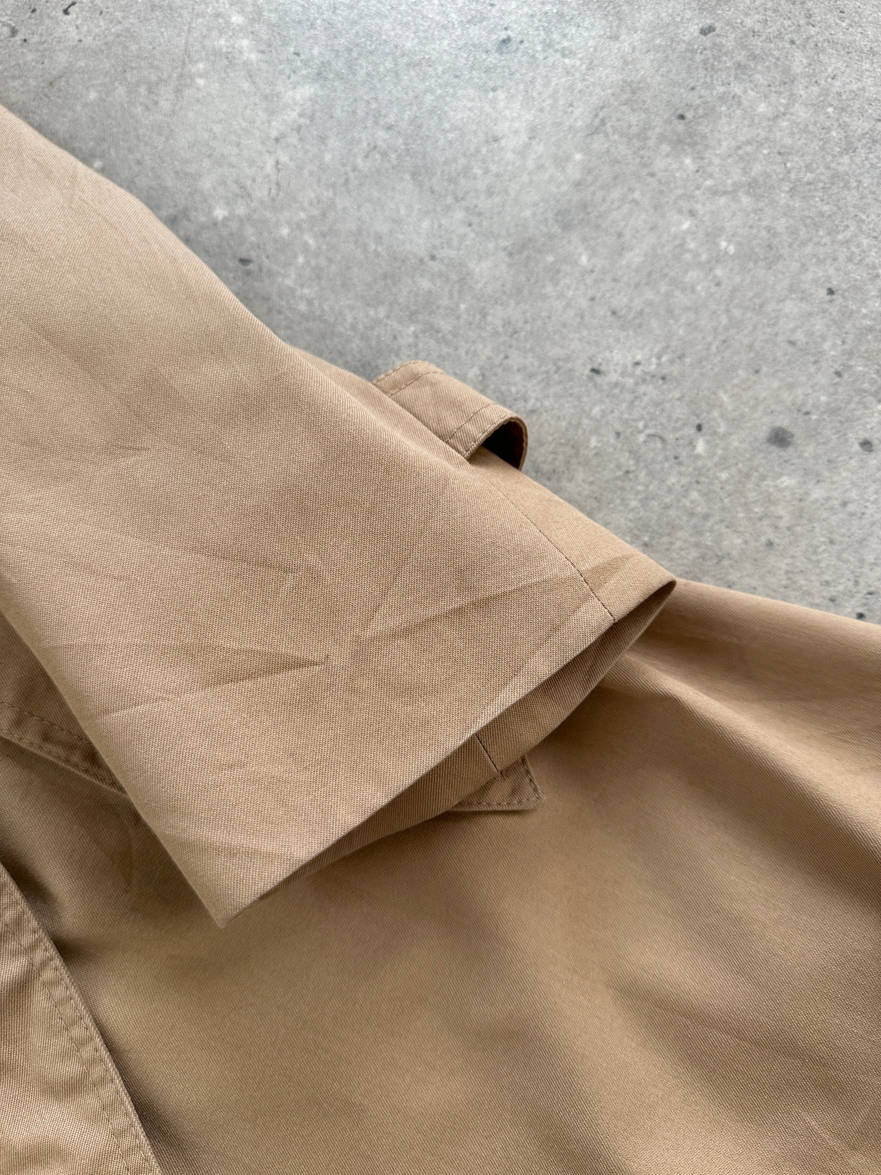 Christian Dior Monsieur cotton single-breasted belted trench coat displayed on a hanger, showcasing classic design and neutral color.