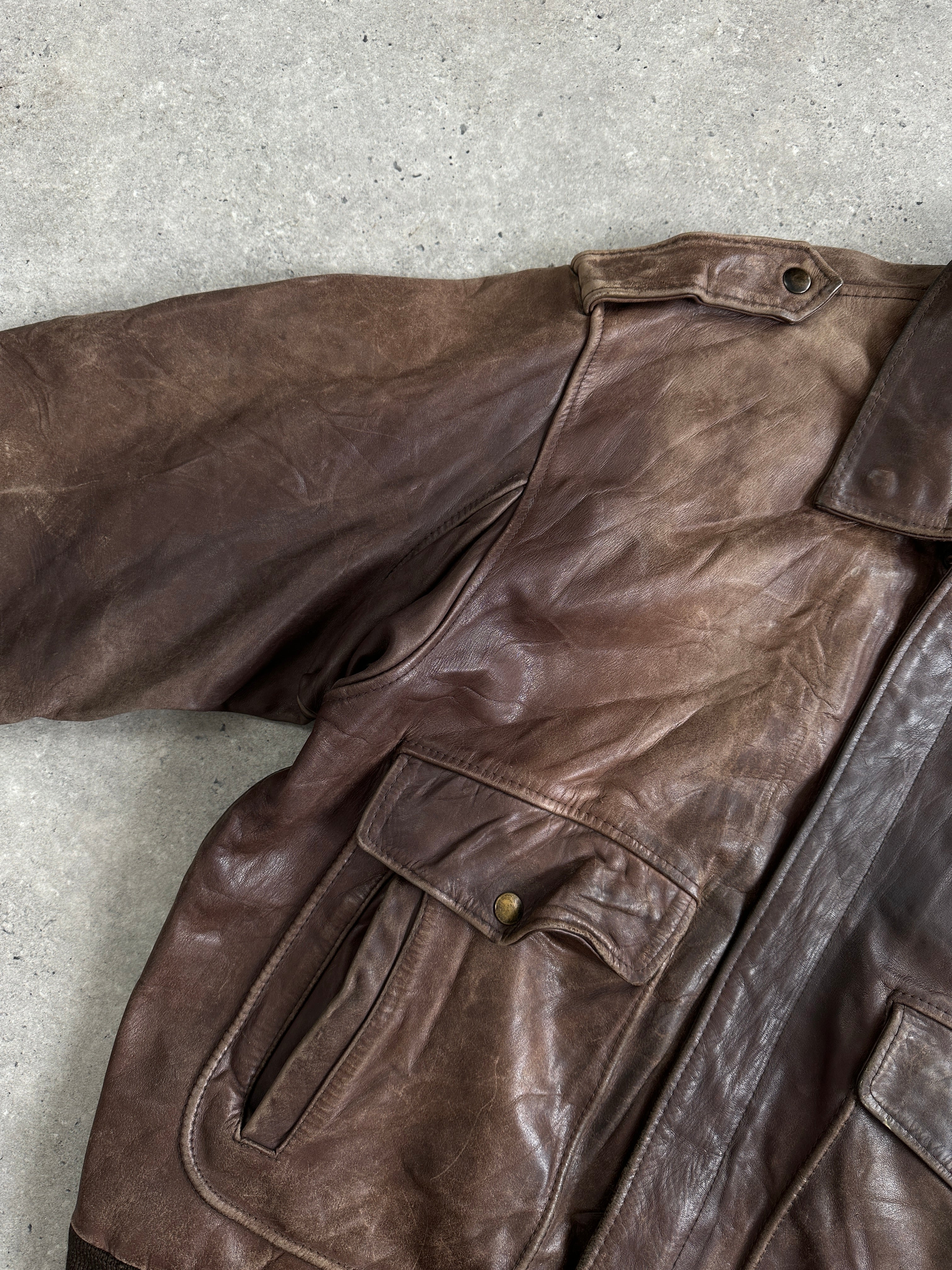 Vintage distressed leather bomber jacket in XL size, featuring rugged style and classic design with visible wear details.