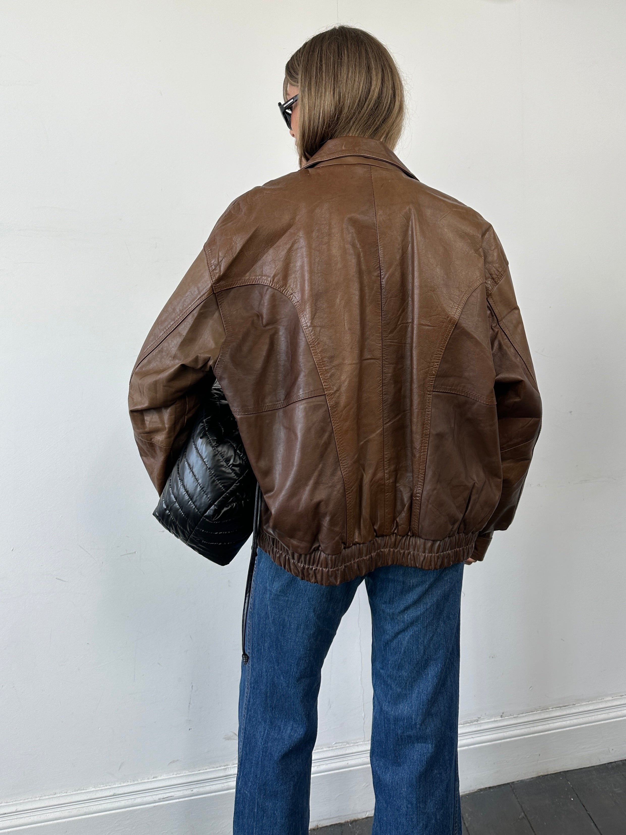 Vintage Tobacco Leather Bomber Jacket in XL, featuring classic design and rugged leather texture, displayed on a hanger.