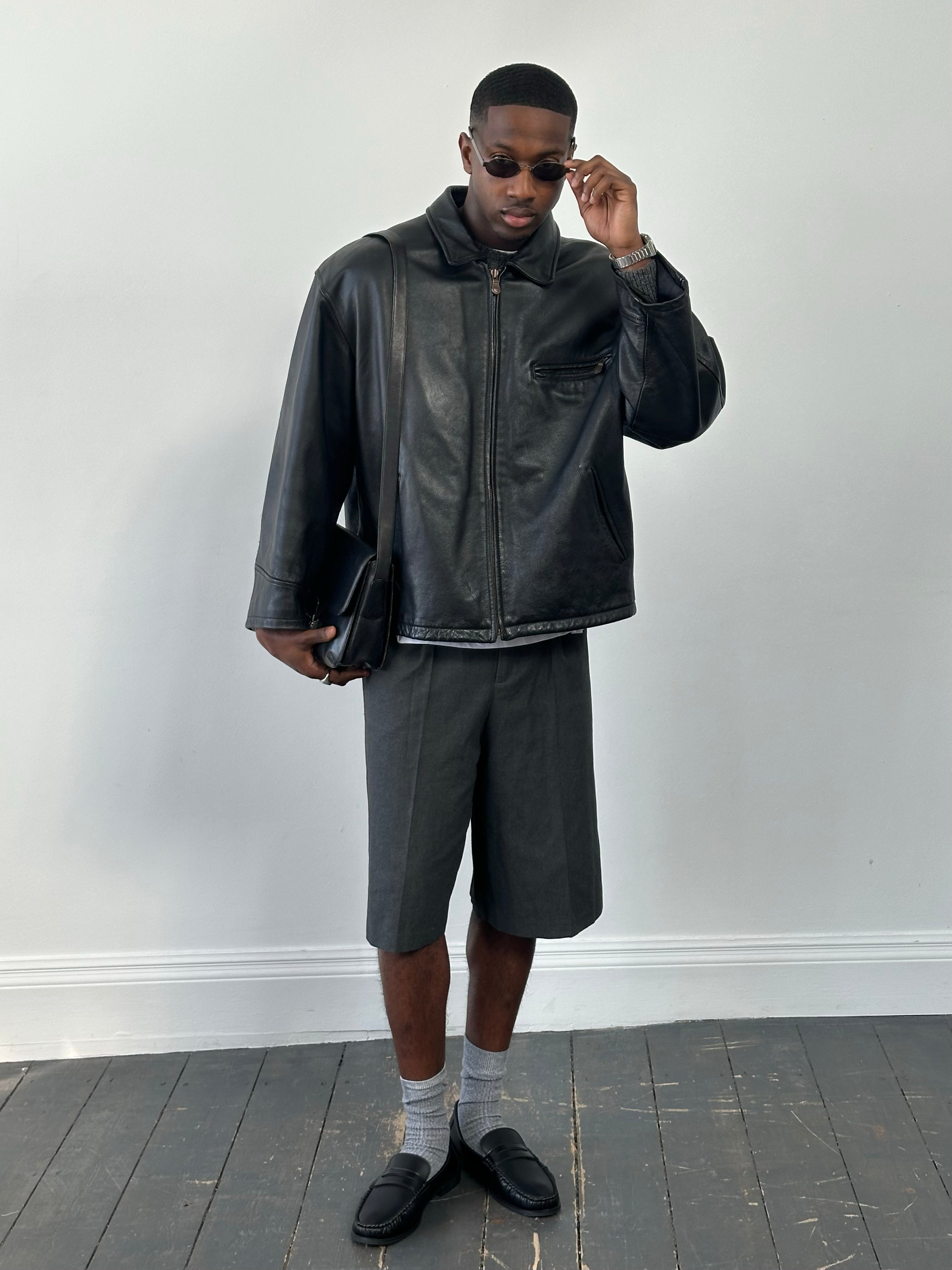 Vintage 1990s heavyweight leather jacket, minimal design, oversized fit, black leather, vintage brand, detailed close-up view.
