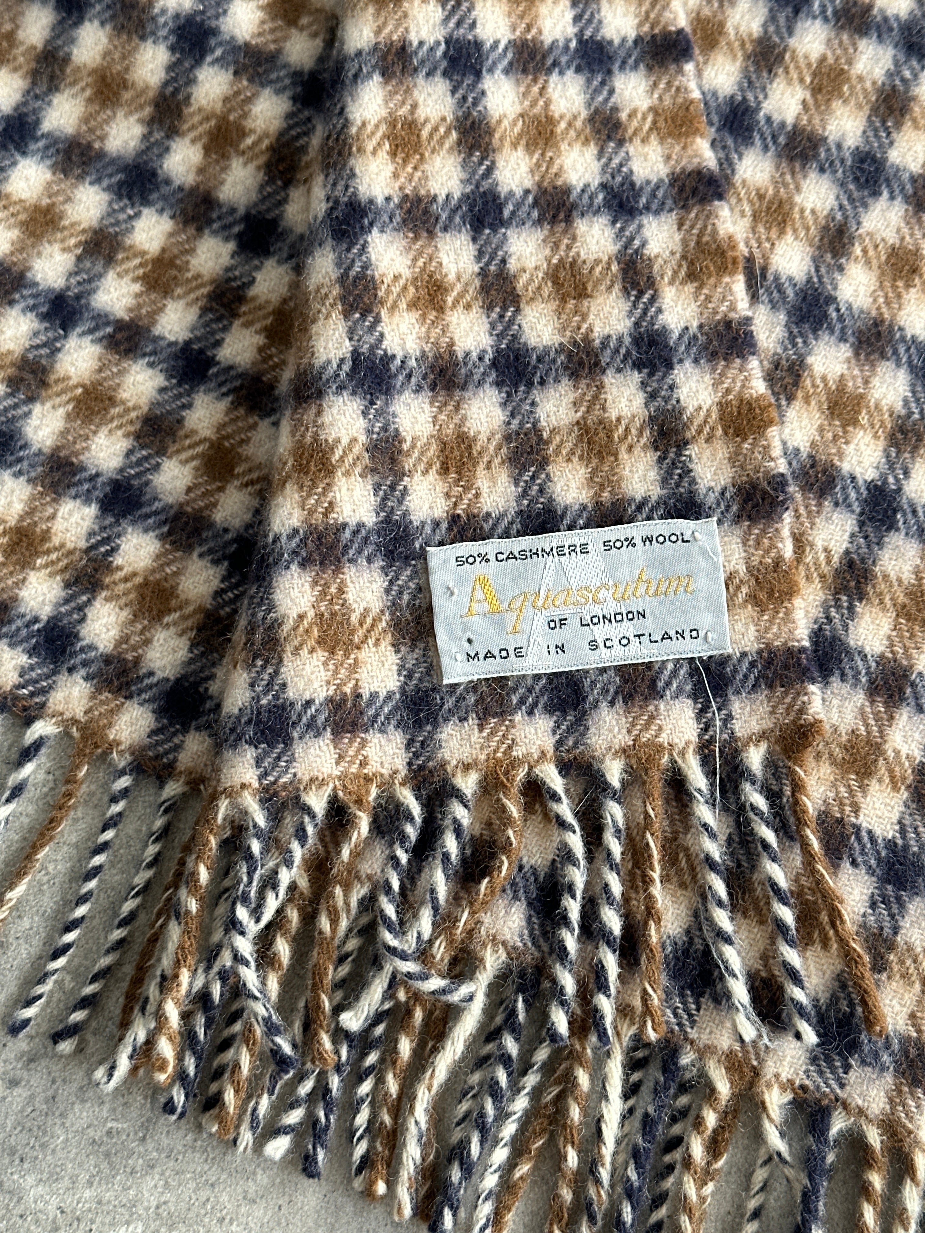 Aquascutum cashmere wool check scarf with classic plaid pattern, soft and warm, draped over a neutral background.