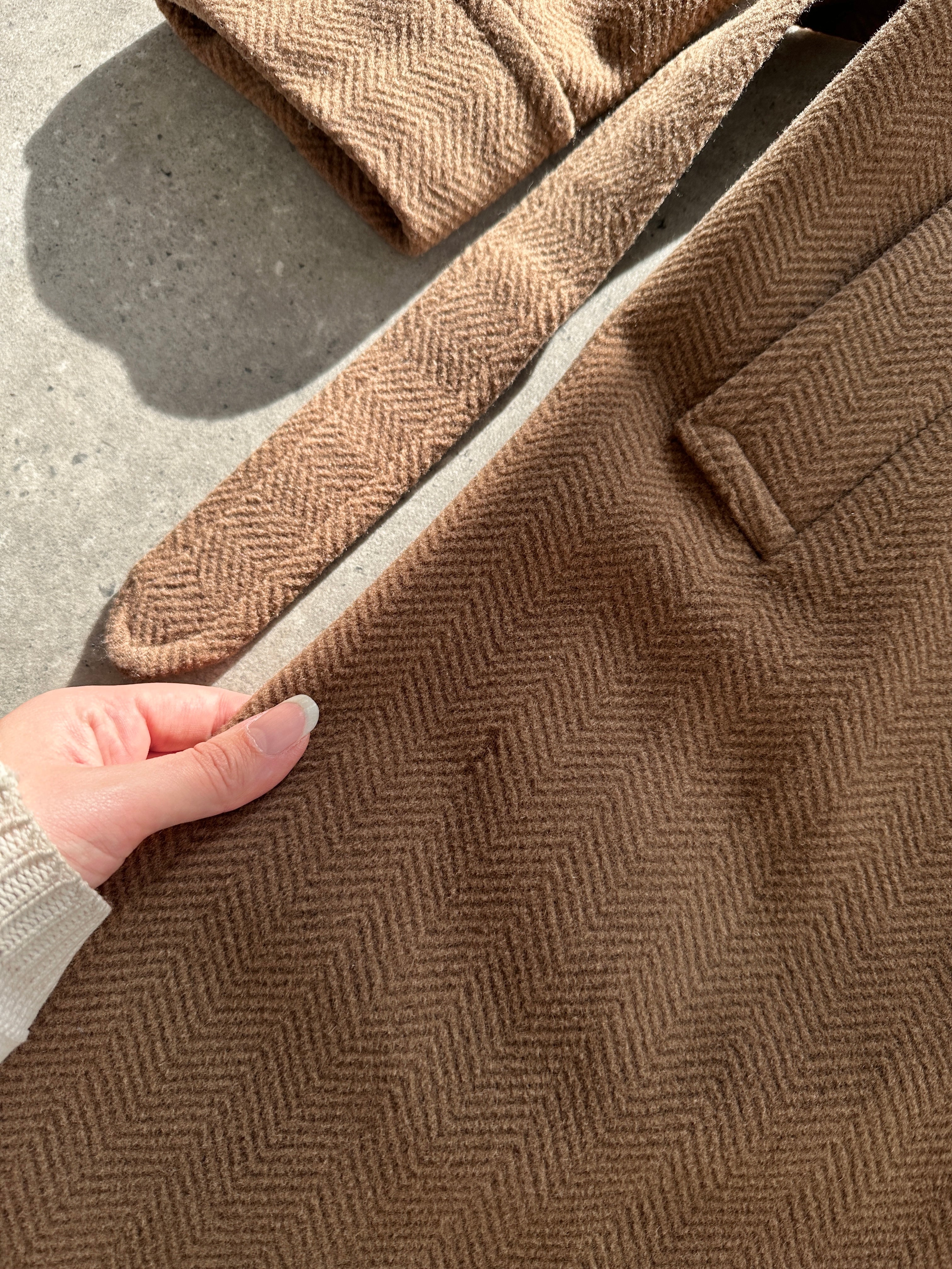 Christian Dior belted double-breasted wool coat in size L, shown hanging with classic tailored design and elegant button details.