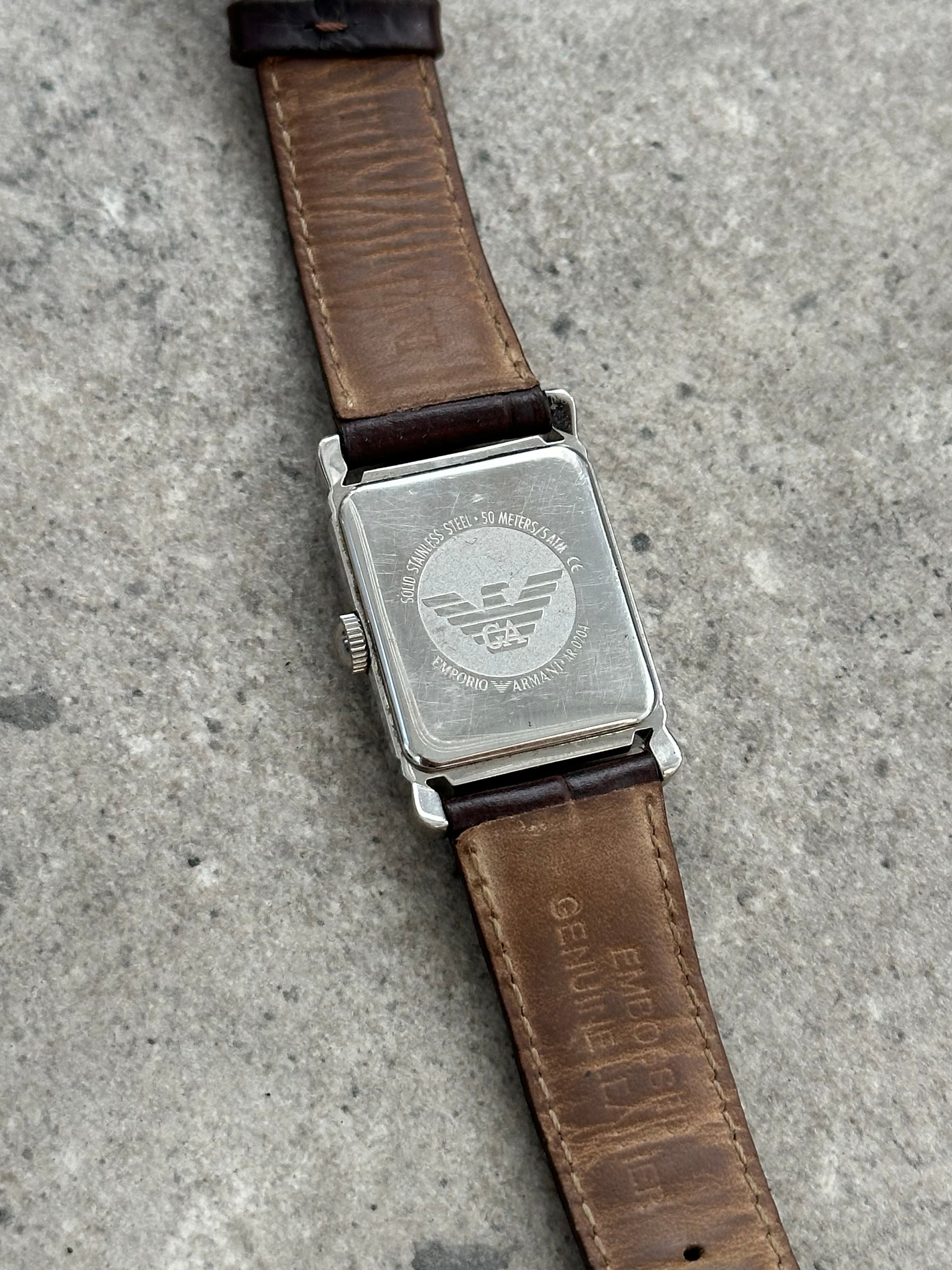 Emporio Armani leather logo watch with round dial and sleek black strap, vintage 2000s style, showcasing the brand’s signature design.