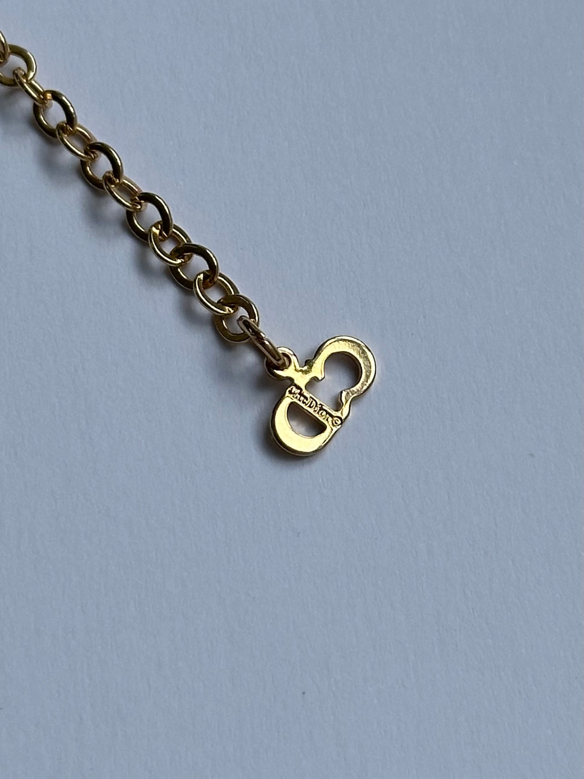 Christian Dior 16-inch gold plated rhinestone drop logo pendant necklace displayed on a white background
