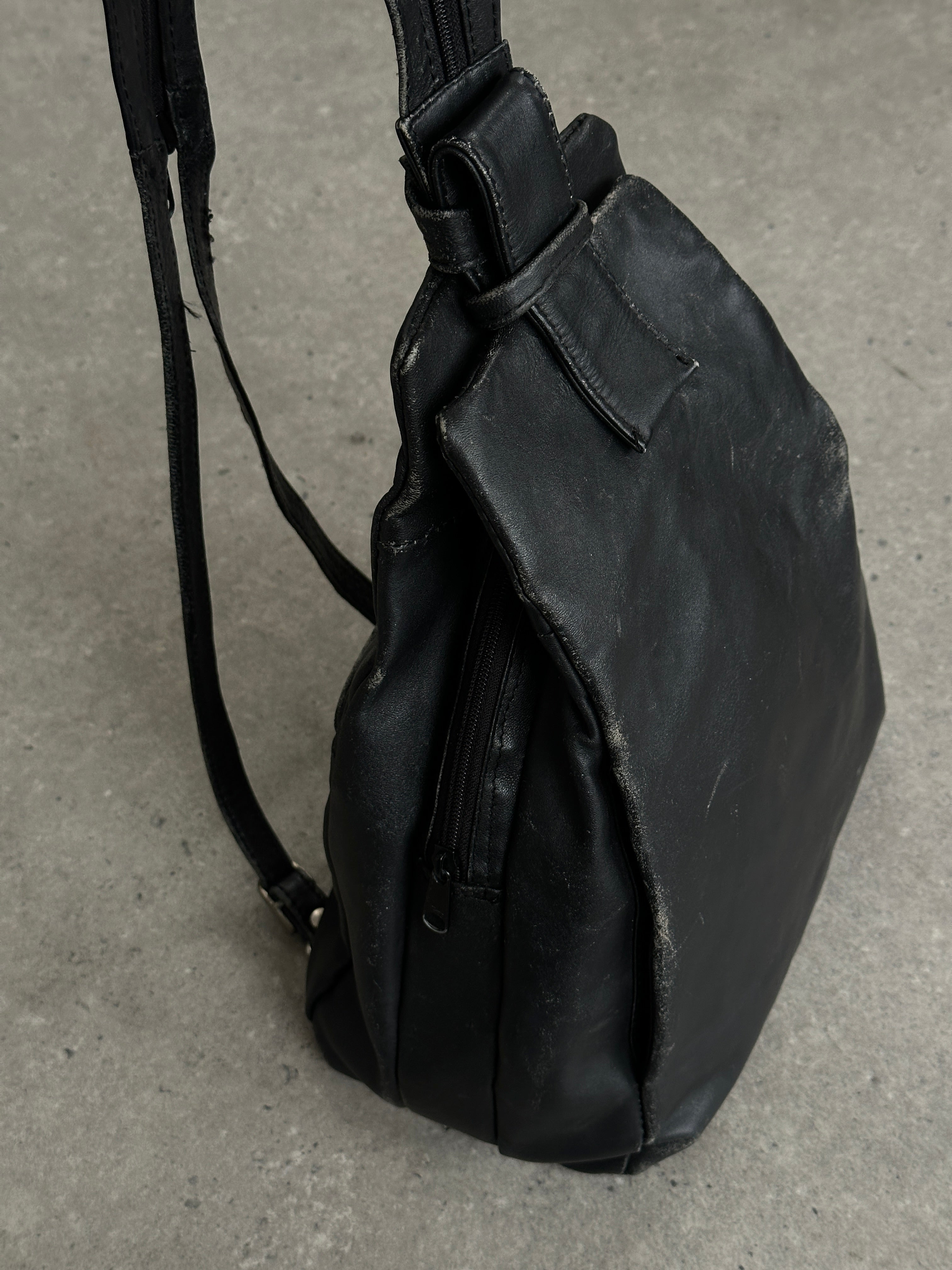 Vintage distressed faux leather rucksack crossbody bag with adjustable strap and vintage-style hardware.