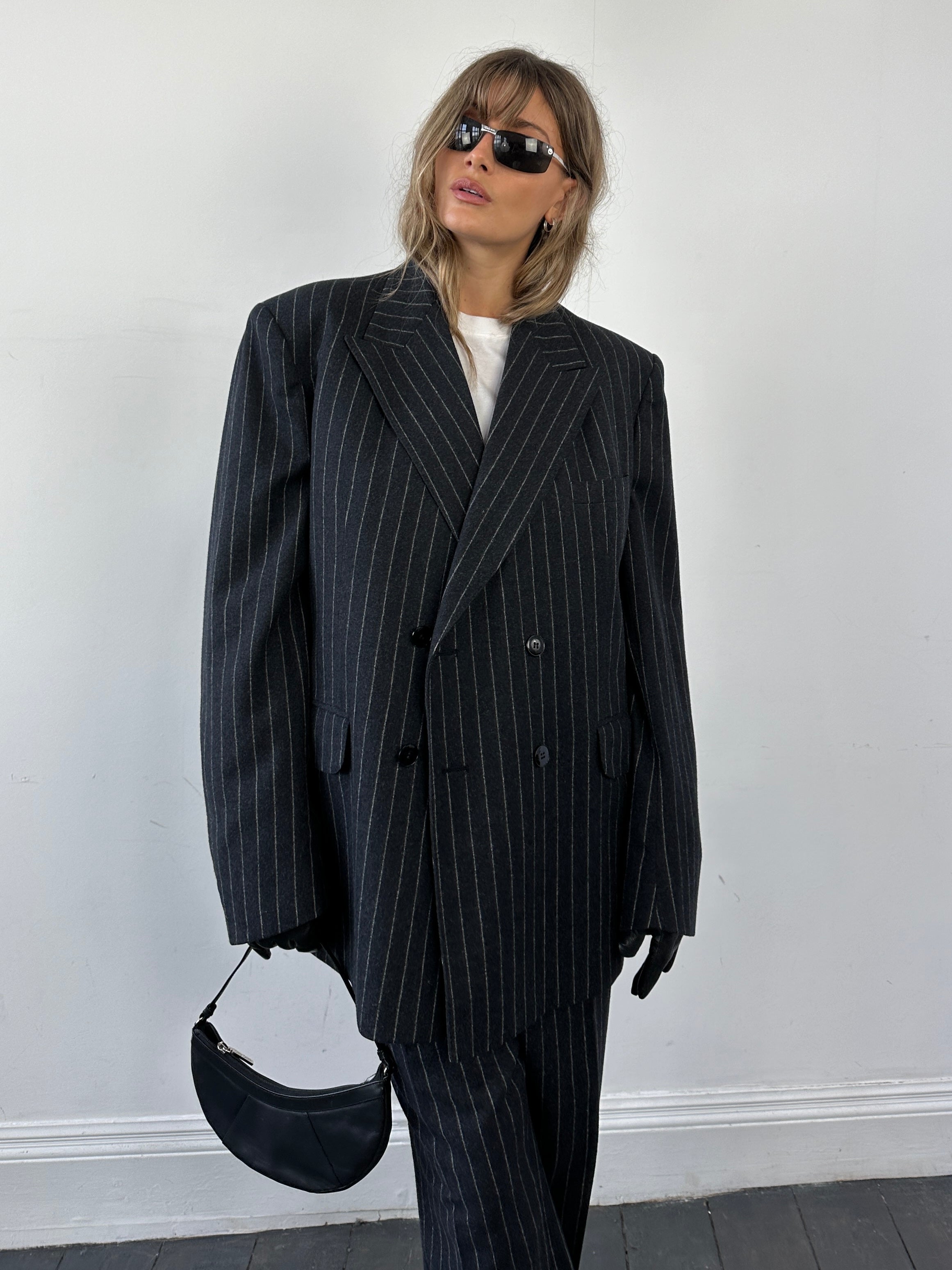 Christian Dior wool double-breasted pinstripe jumpsuit with tailored fit, featuring lapels, long sleeves, and classic suit styling.