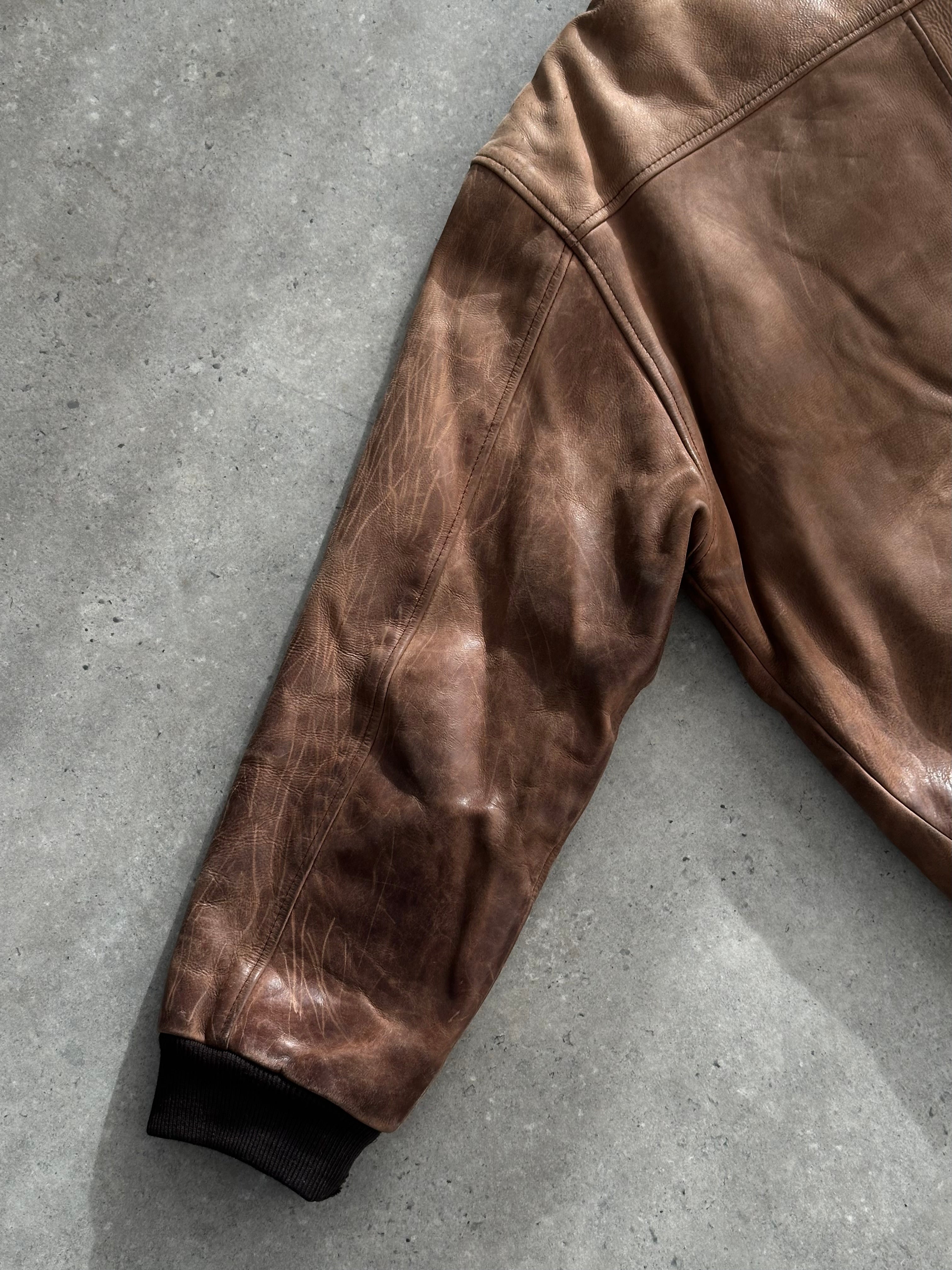 Vintage distressed leather bomber jacket in XL, featuring rugged design and classic style, displayed on a hanger.