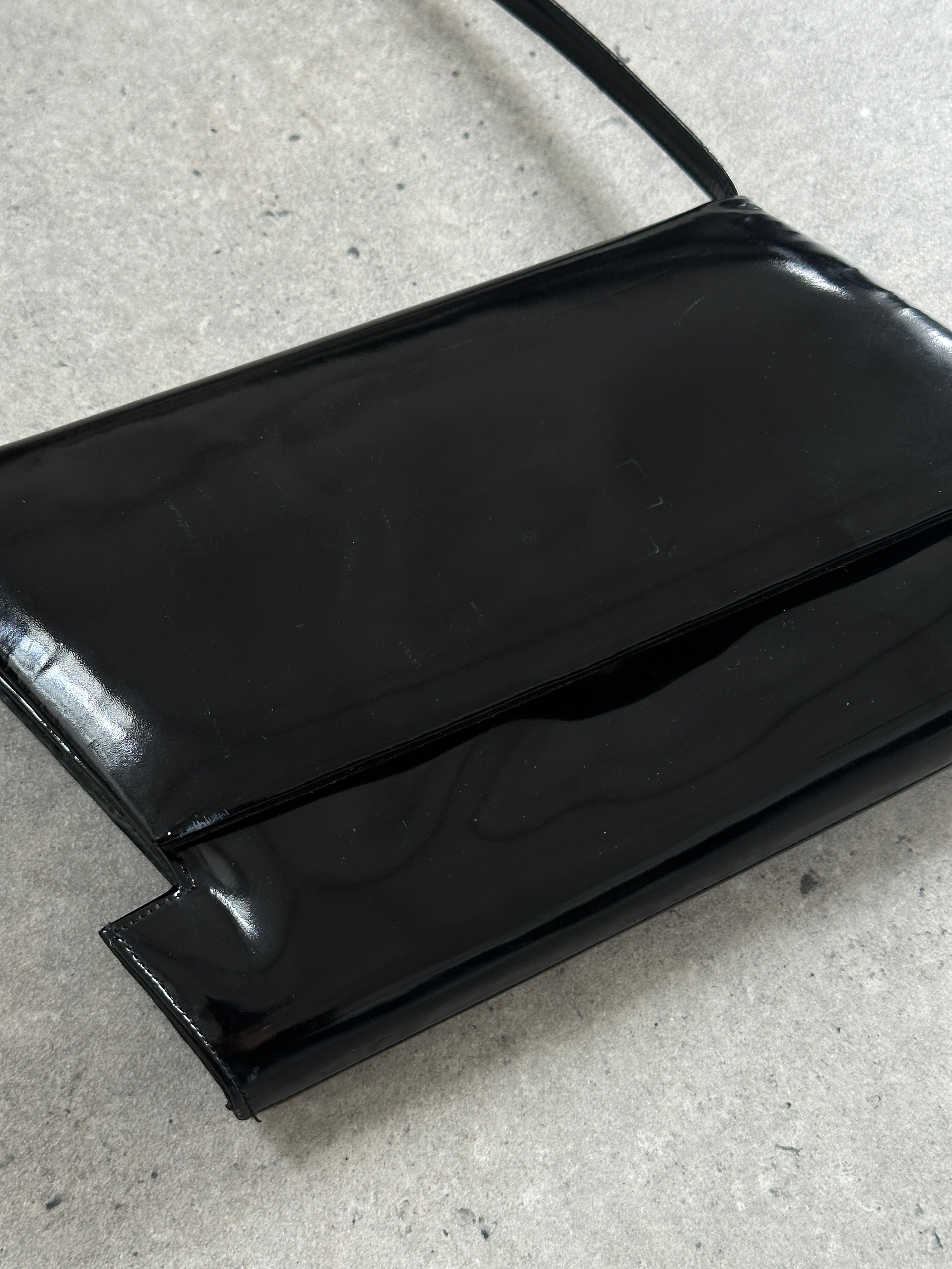 Charles Jourdan 1990s asymmetric patent crossbody bag with sleek design and modern style, featuring a glossy finish and adjustable strap.