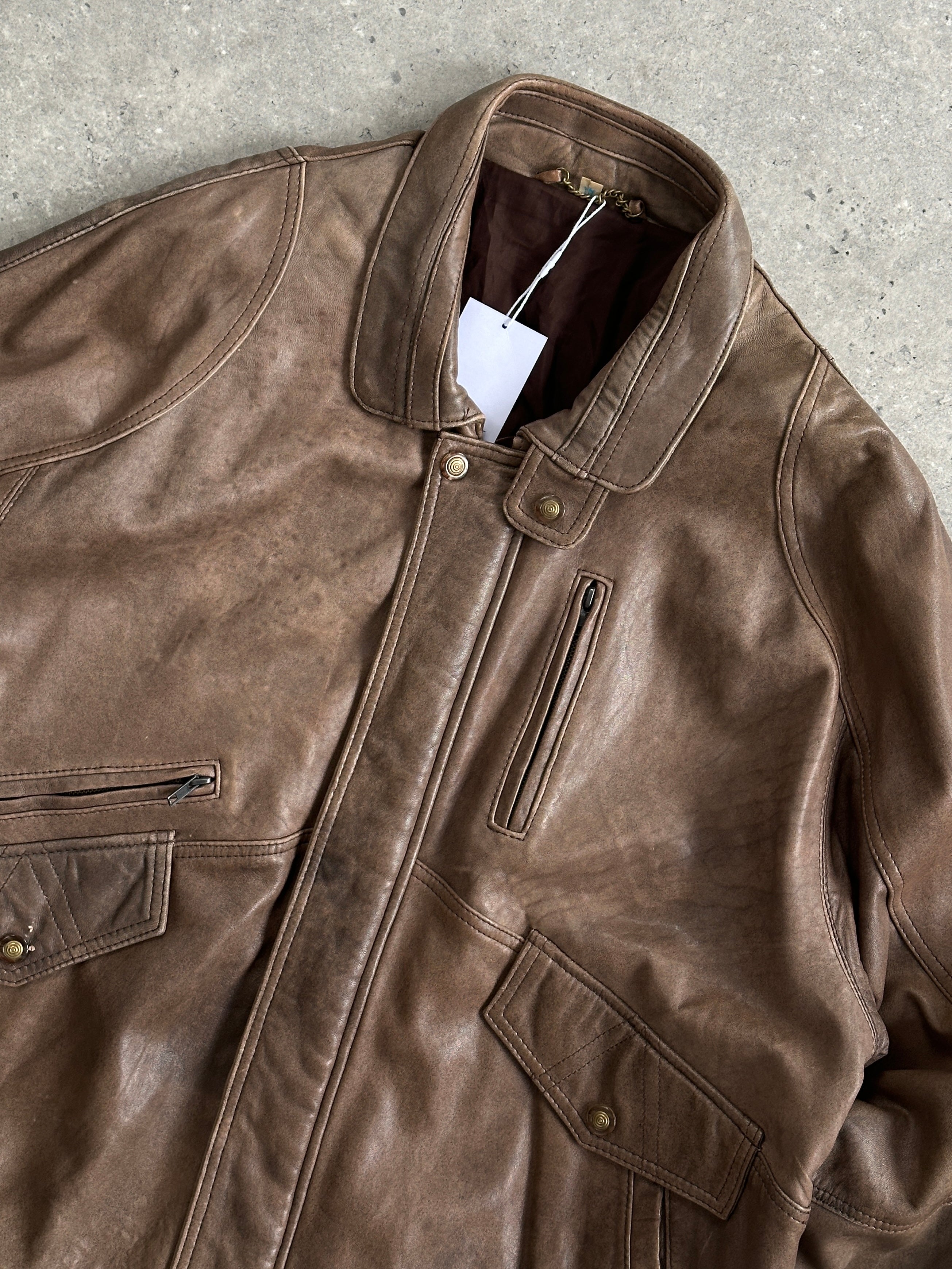 Vintage leather bomber jacket in XL/XXL, showing classic design, brown leather material, and ribbed cuffs and collar.