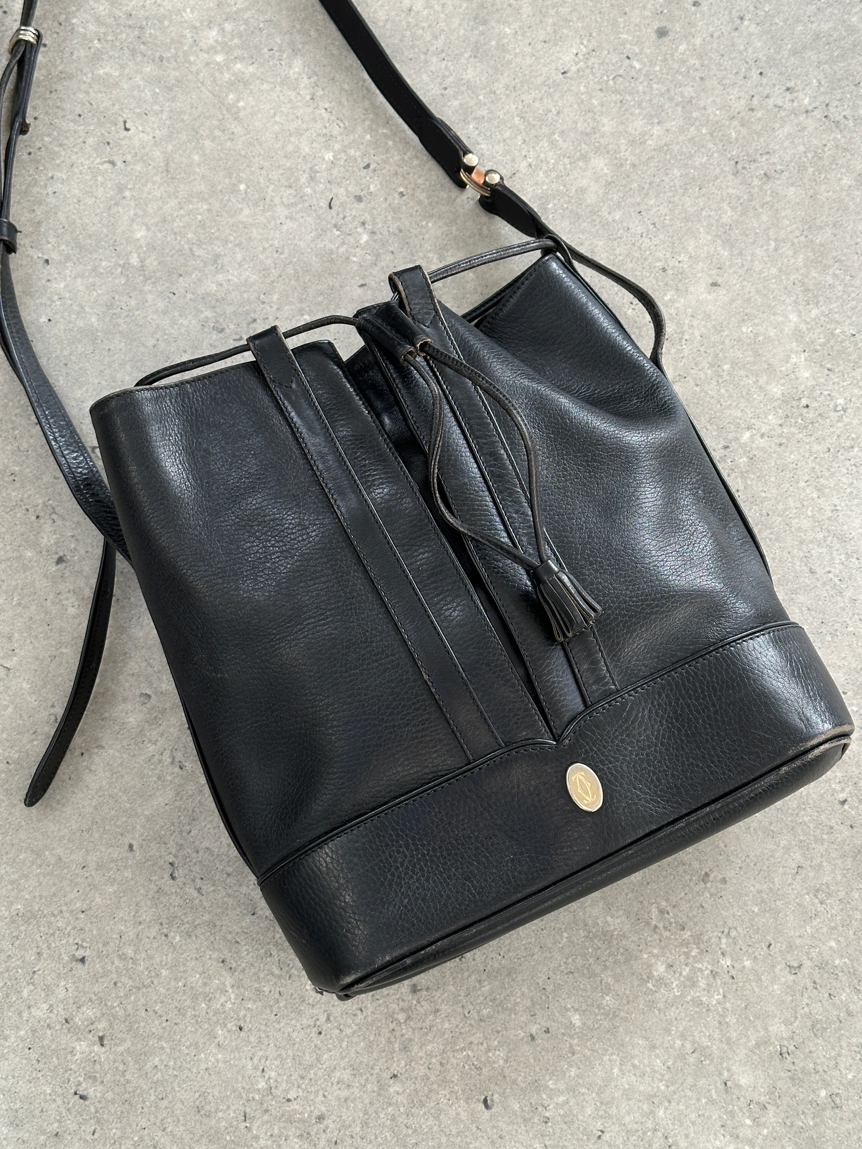 Cartier 1980s leather bucket bag with drawstring closure and vintage design, featuring smooth leather and subtle branding.