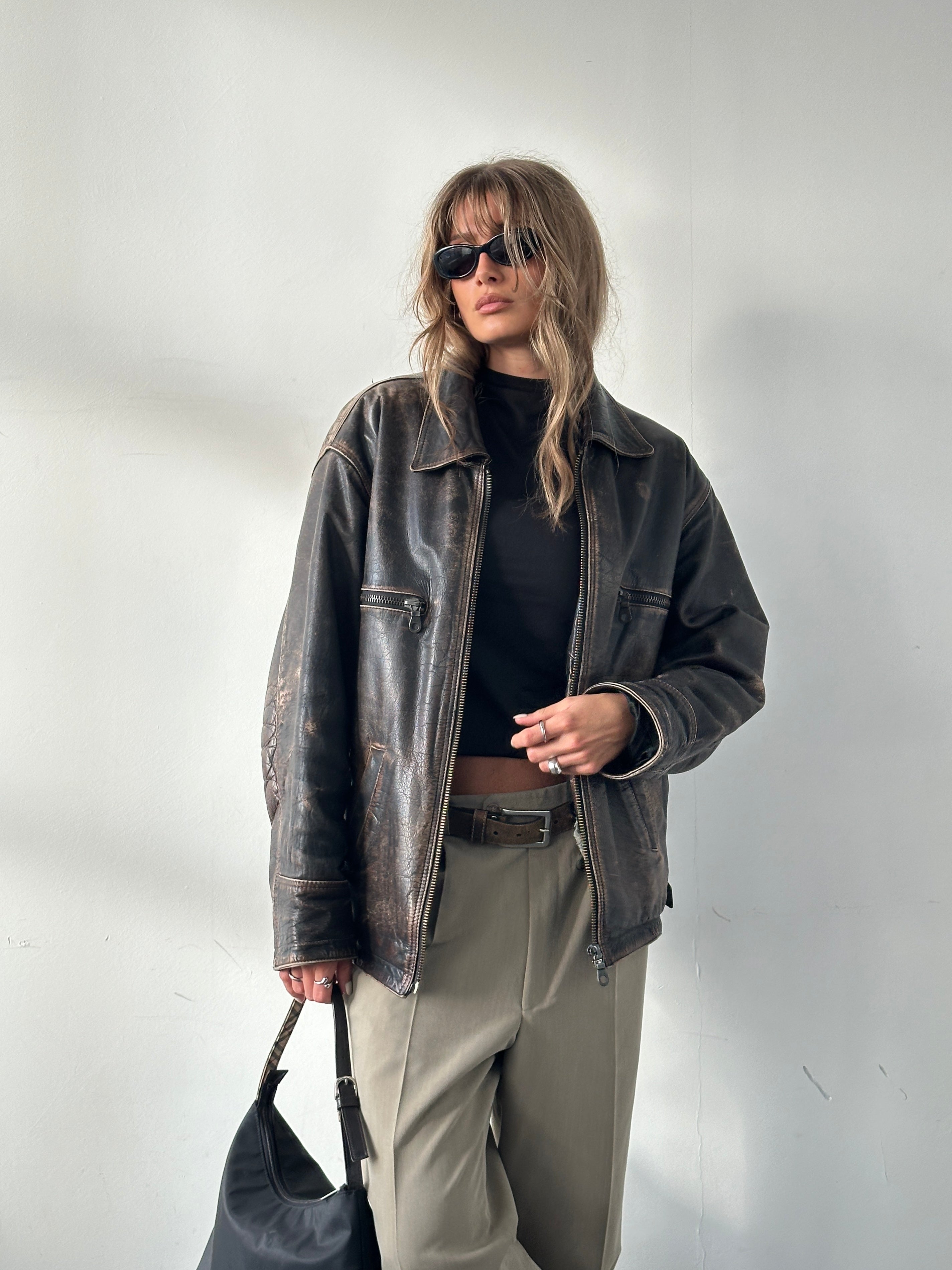 Vintage distressed leather jacket in size M/L, featuring rugged style and classic design, displayed on a neutral background.