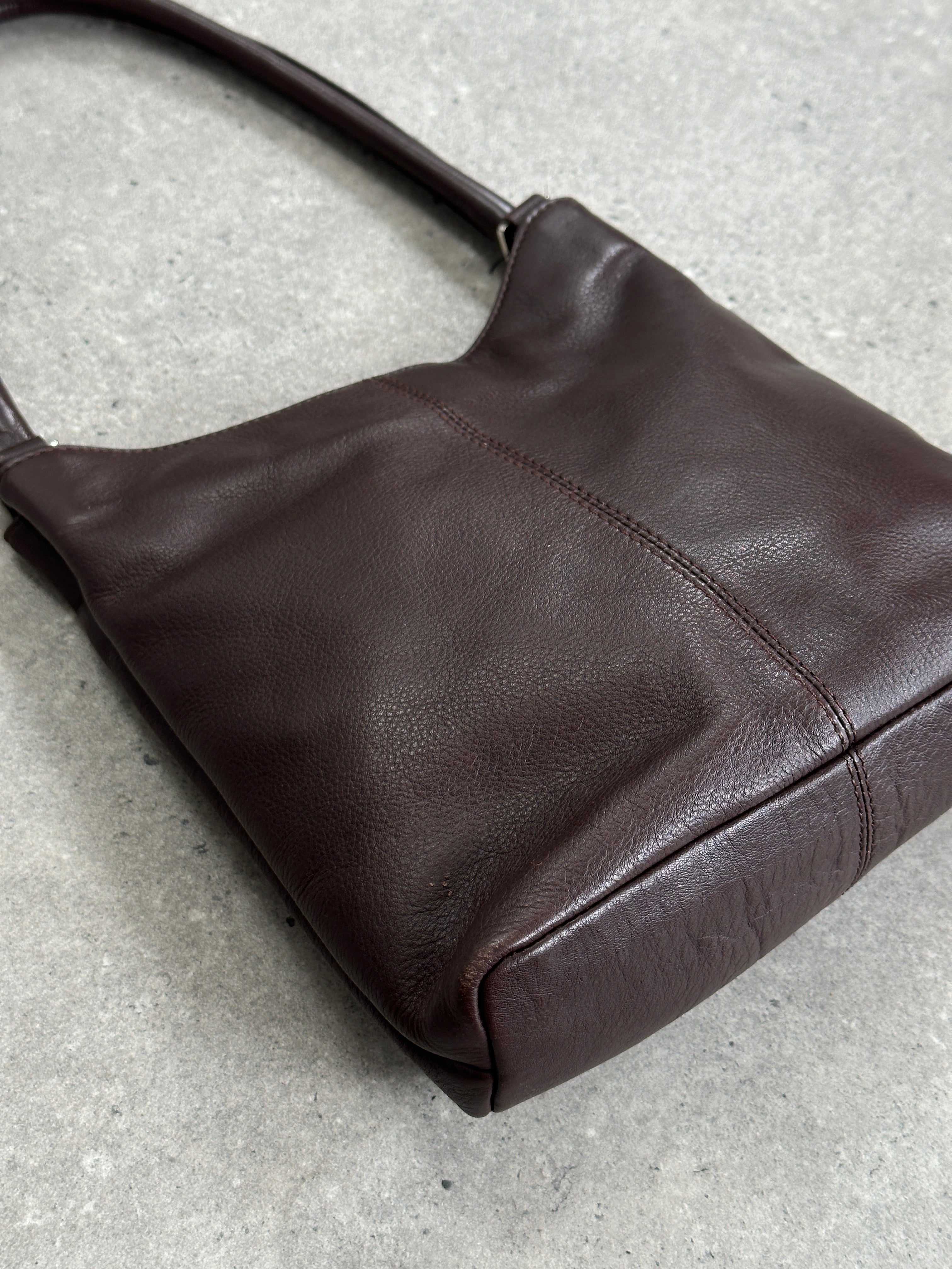 Vintage leather shoulder bag with adjustable strap and classic design, showcasing rich tan leather and detailed stitching.