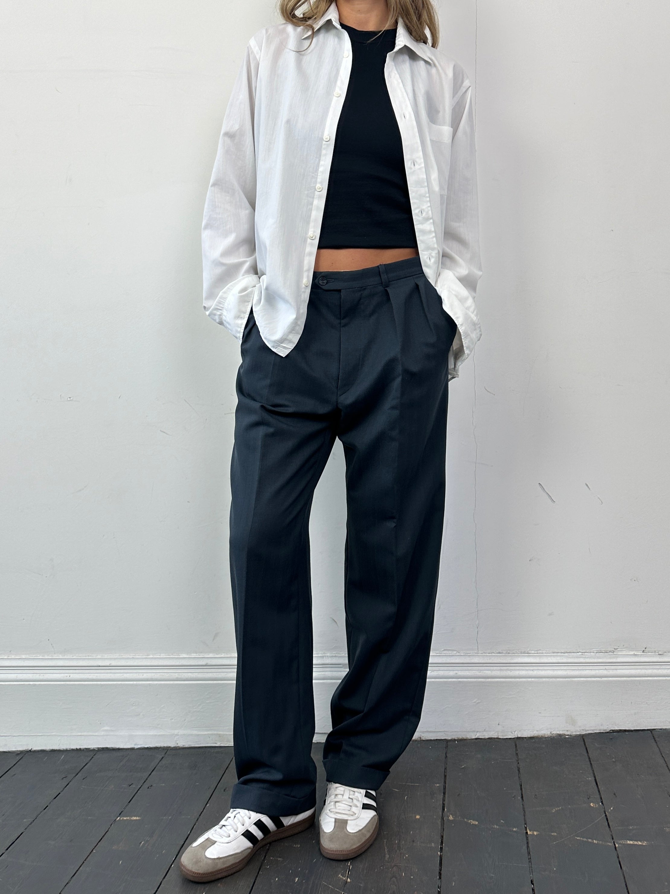 Christian Dior wool tapered leg tailored trousers in dark color, showing the sleek, structured fit and fabric texture.
