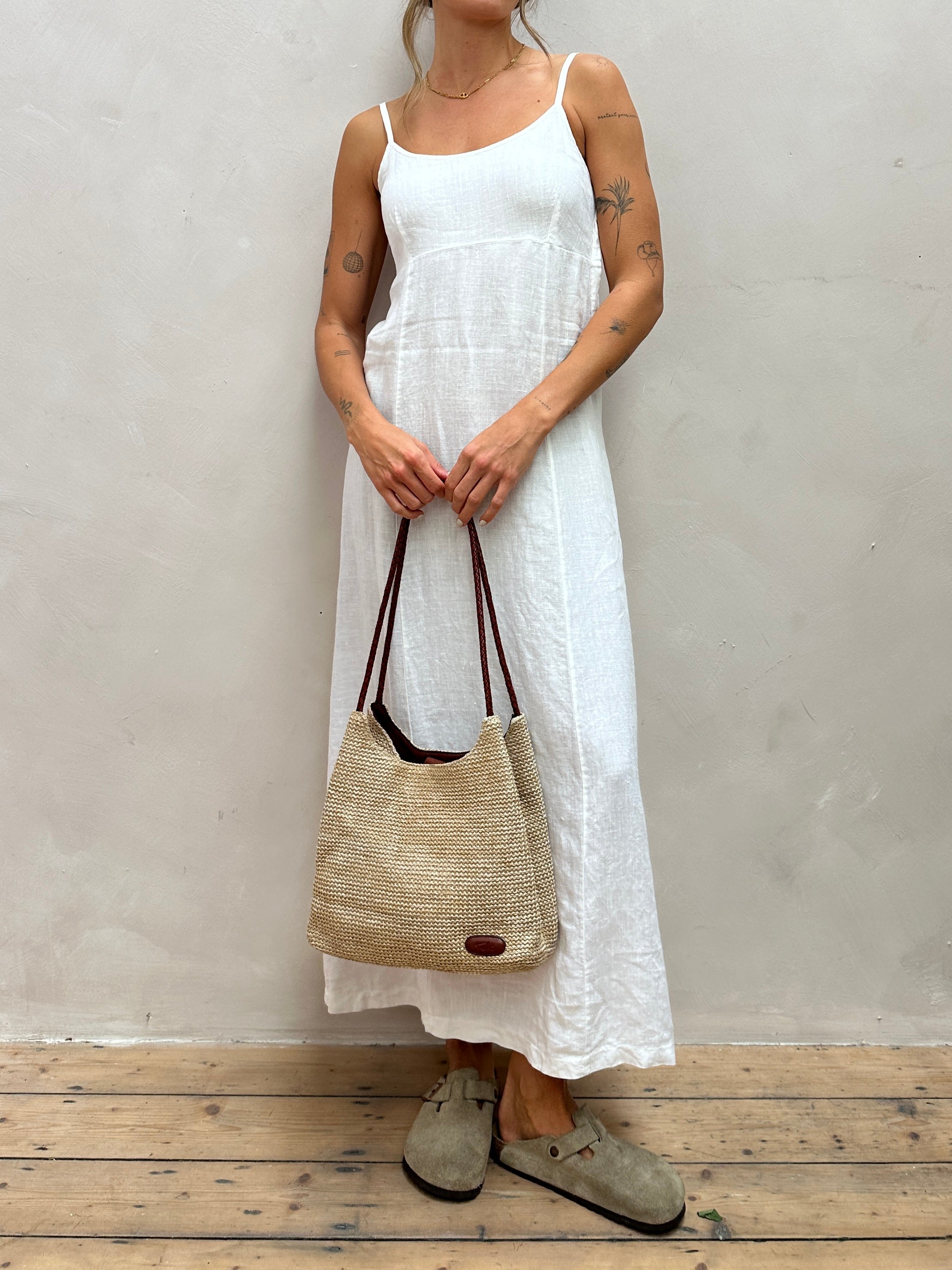 Vintage leather and straw shoulder bag with adjustable strap, featuring a rustic design and handcrafted details.