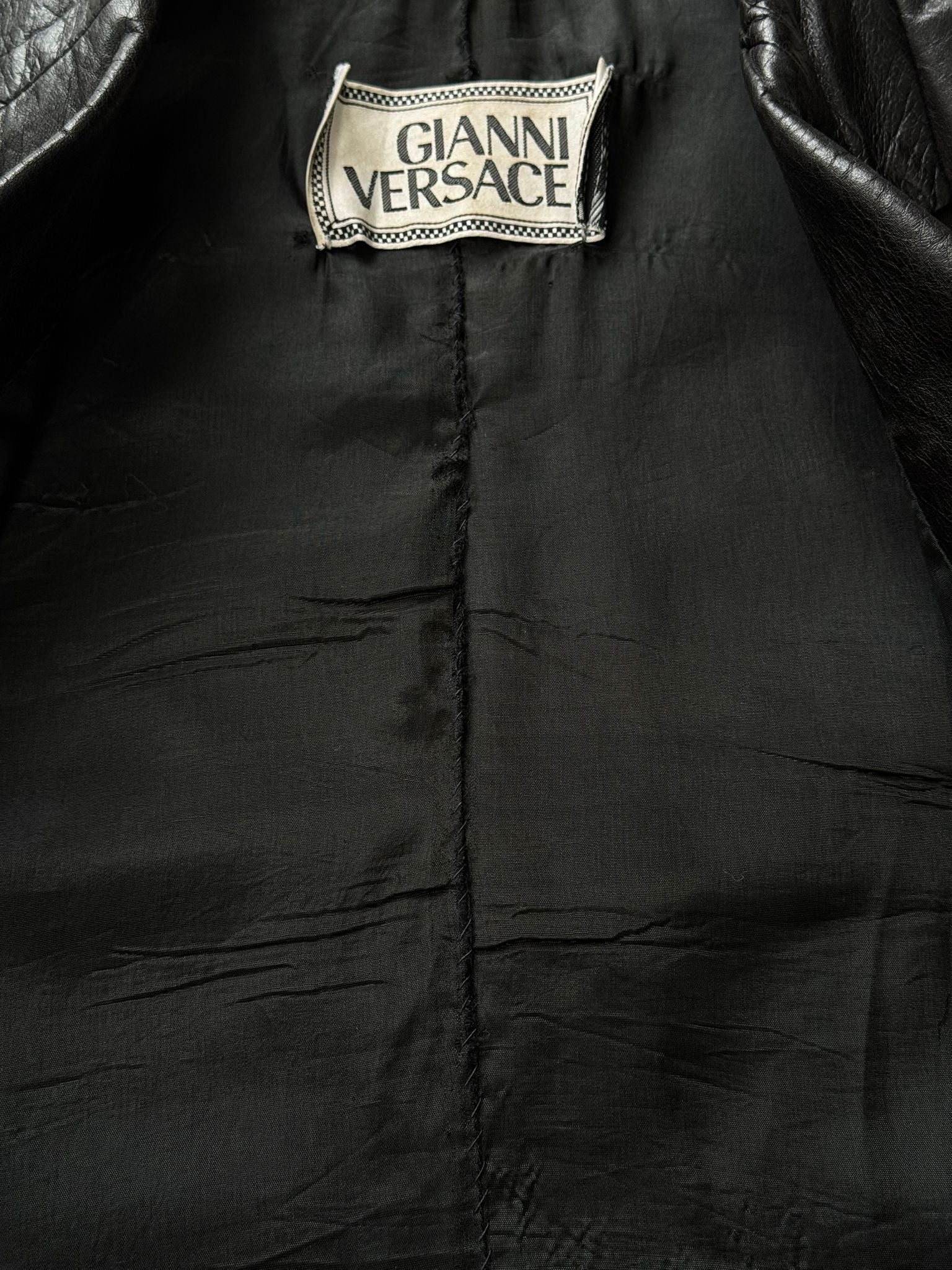 Versace 1990s fitted leather jacket in XS, black designer leather jacket with classic style and sleek silhouette.