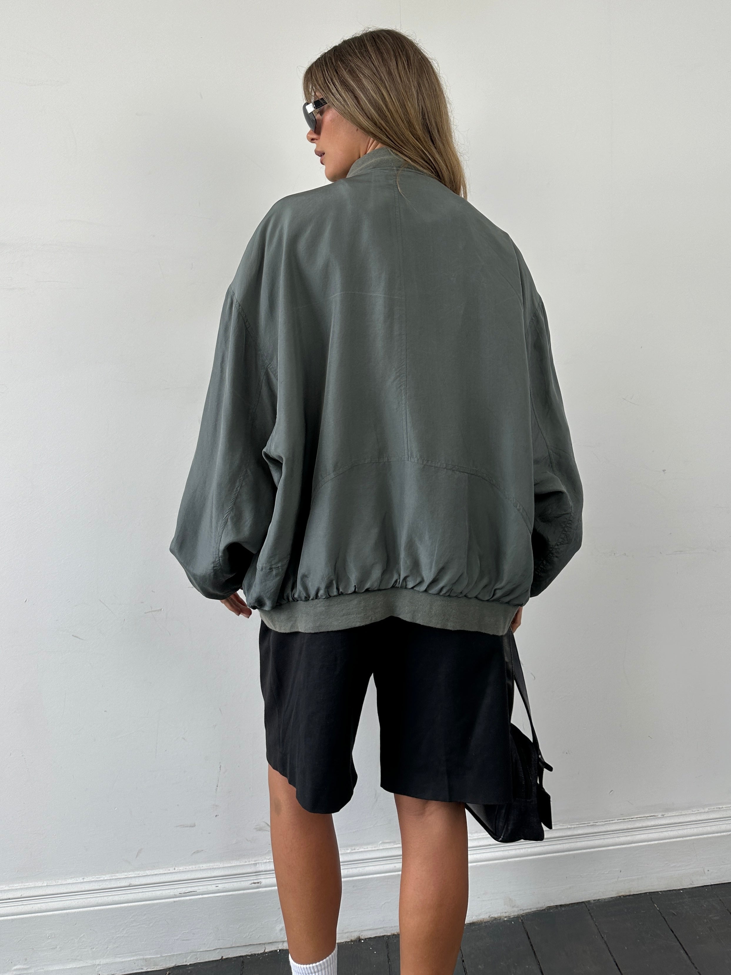 Vintage 80s pure silk bomber jacket in XXL, featuring a classic design and smooth silk fabric, displayed on a hanger.