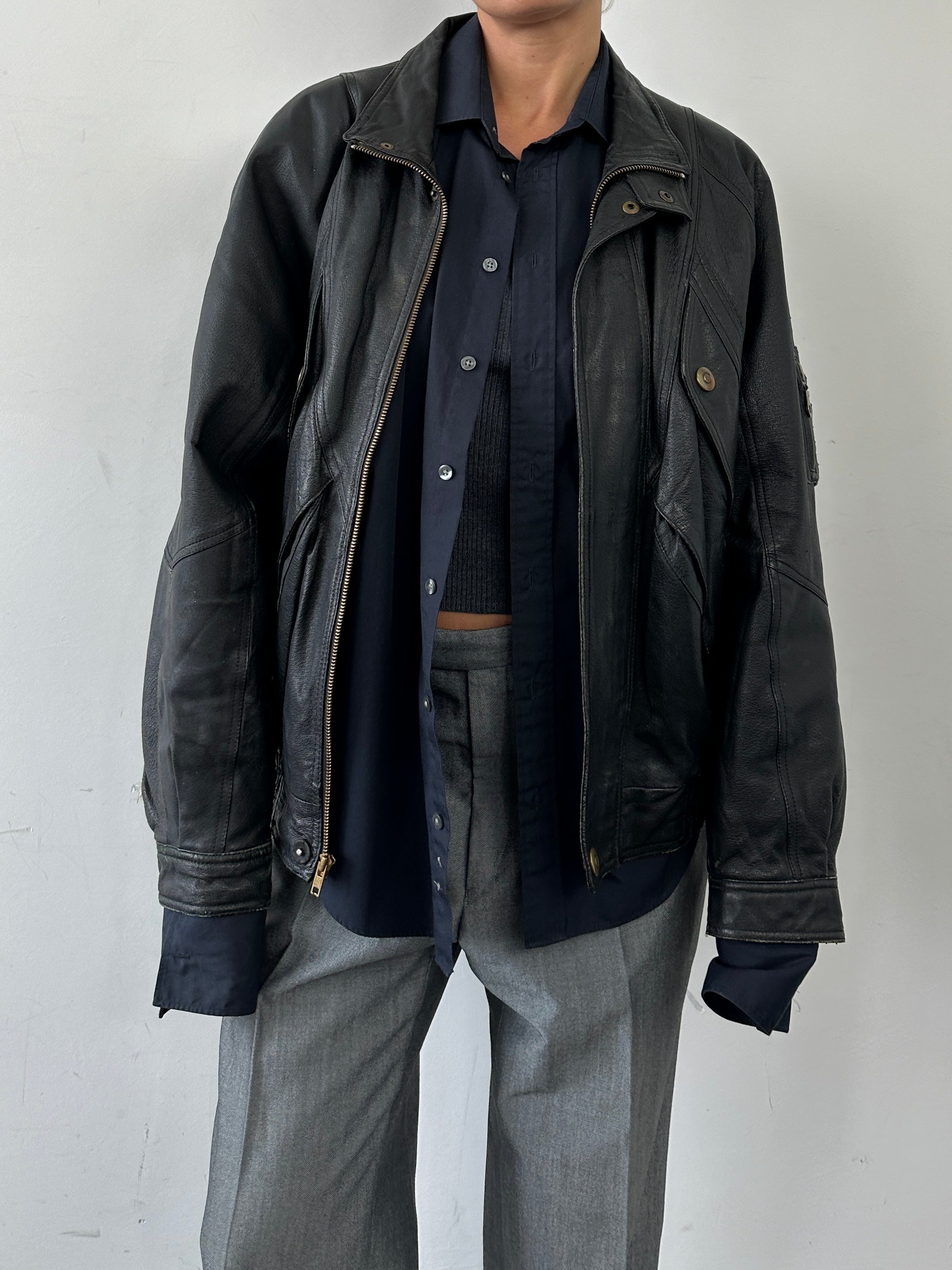 Vintage leather bomber jacket in size L/XL, featuring classic design and durable construction, shown on a hanger.